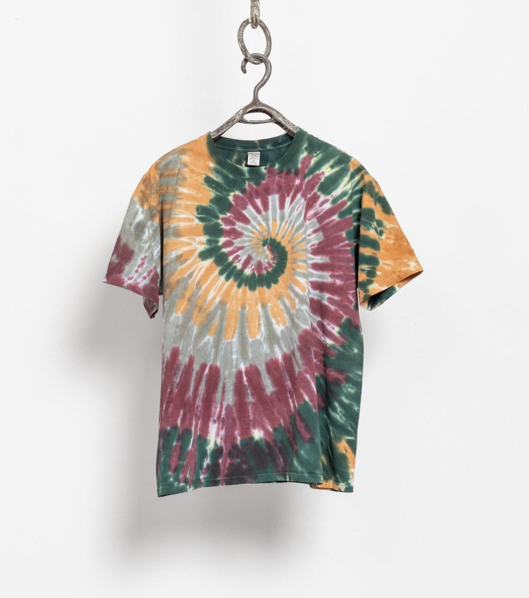 A vintage earthy spiral tie-dye t-shirt in multicolor pattern, displayed on a hanger against a white background.