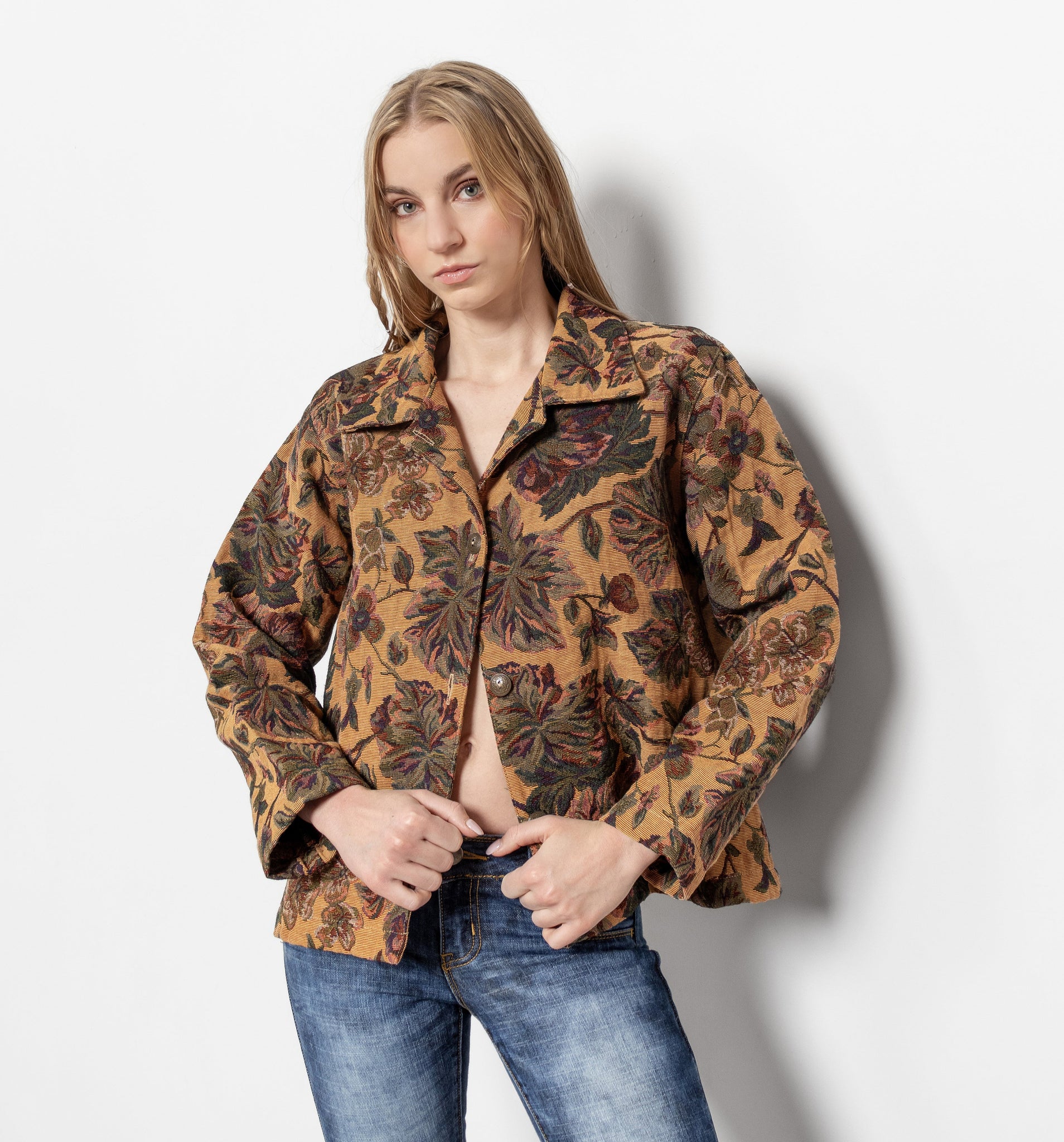 Woman wearing a patterned jacket and jeans on a white background