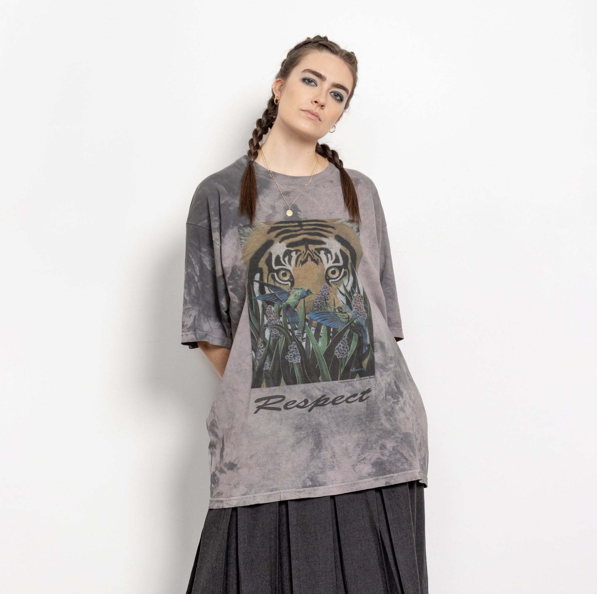 A person wearing a vintage 90's style tie-dye t-shirt with a tiger and butterflies graphic, in a color that appears to be grey. The t-shirt has the word 'Respect' printed on it.