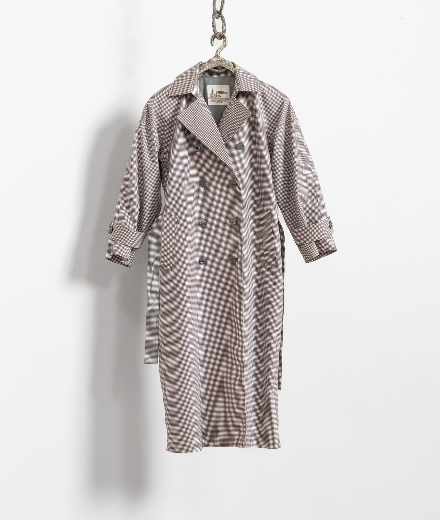 Gray trench coat hanging on a white background