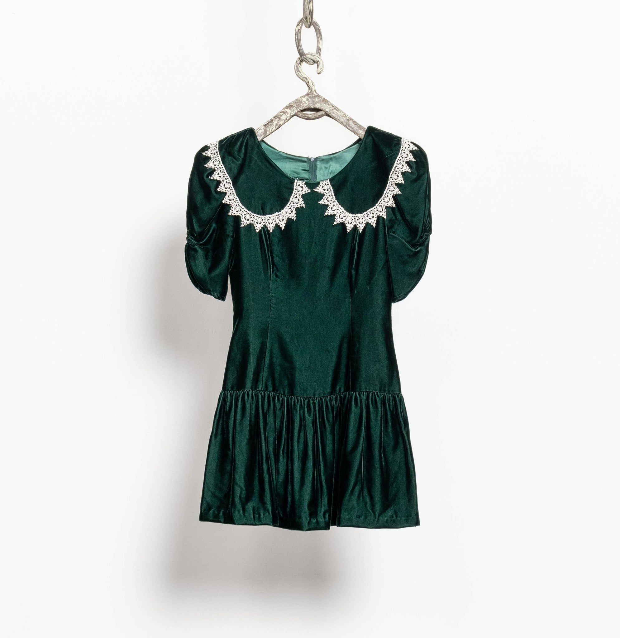 Green dress with decorative collar on a hanger against a white background