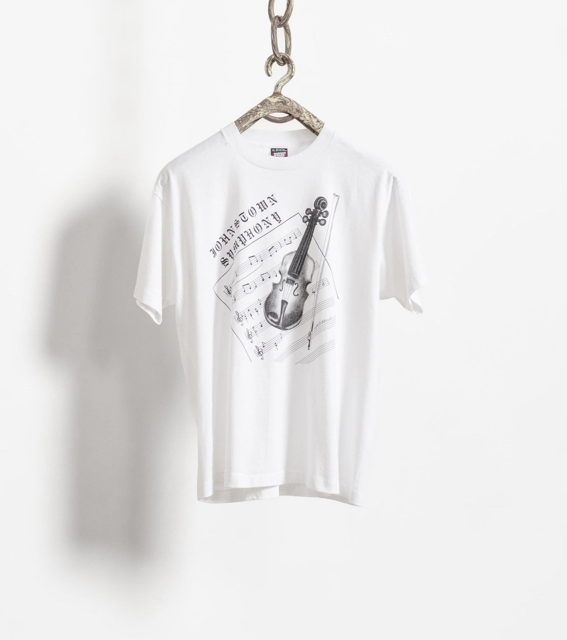 White t-shirt with musical design on a hanger against a white background