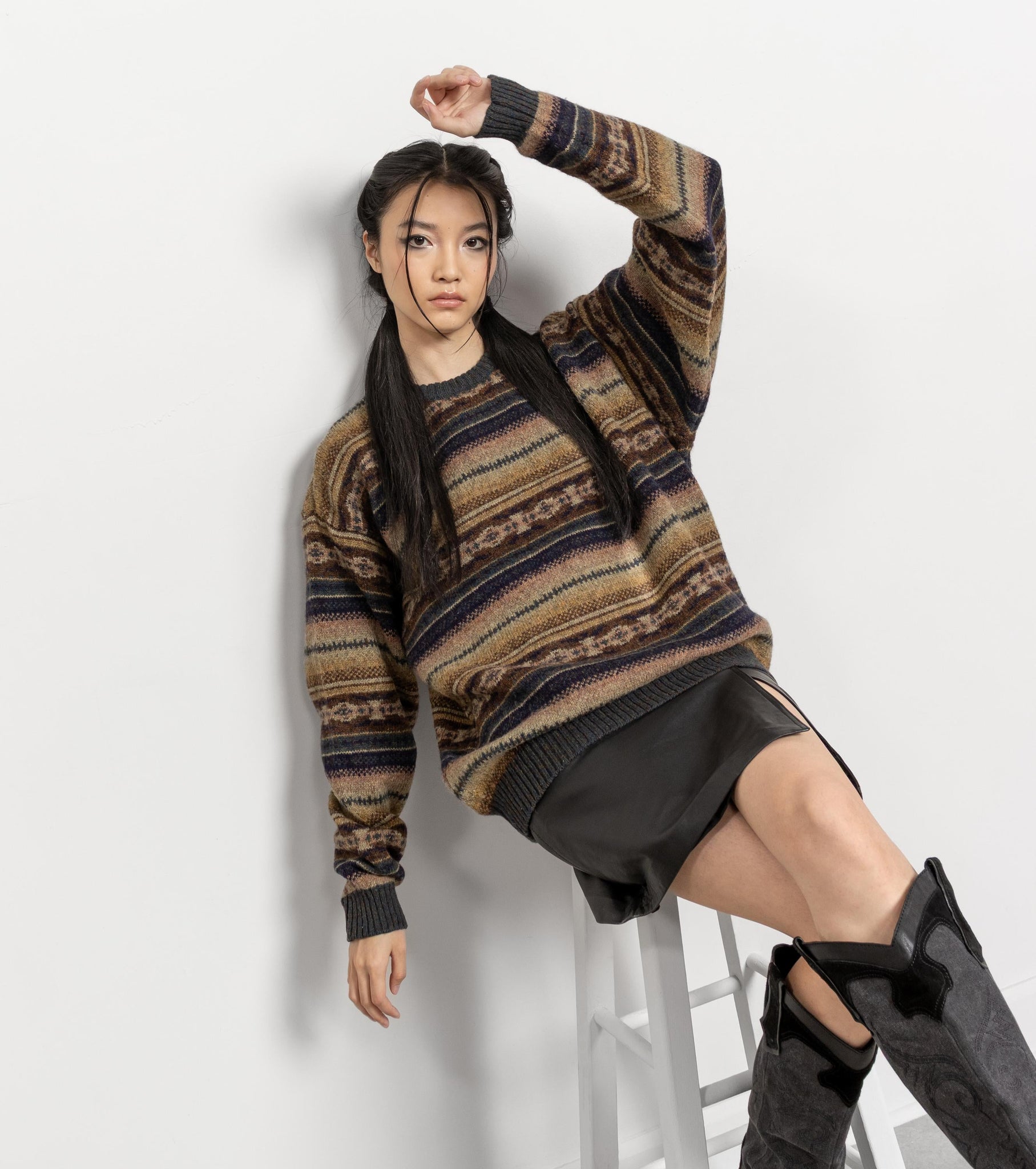 Woman wearing a patterned sweater and black skirt on a white background