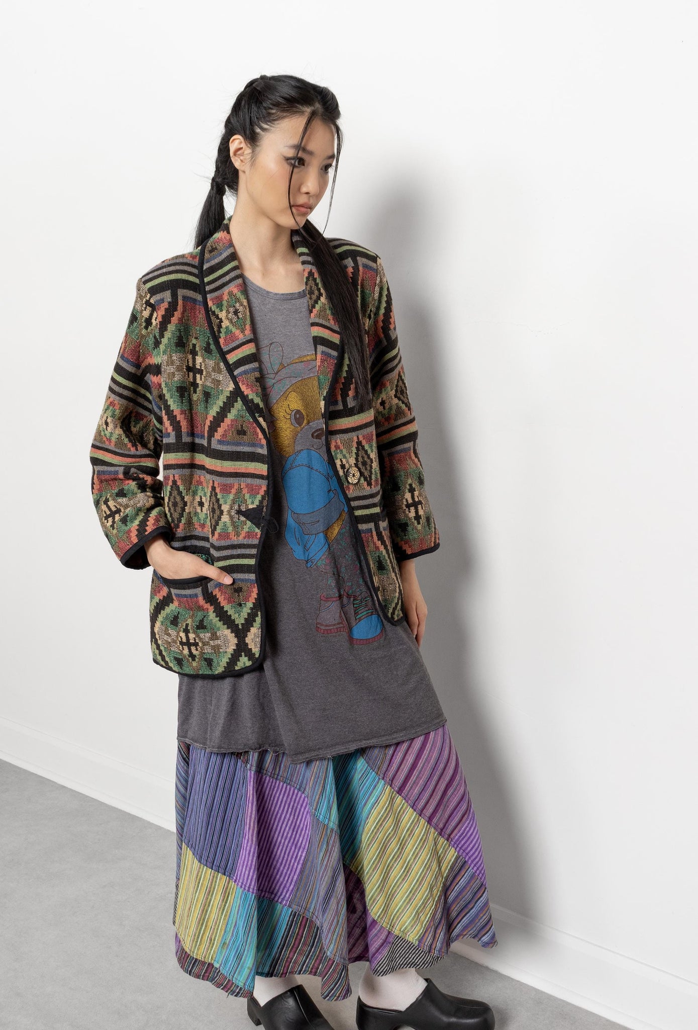 Person wearing a colorful patterned coat and skirt against a white background