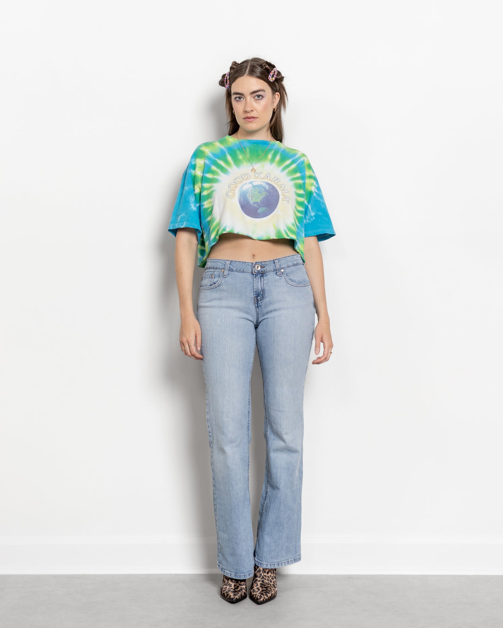 Person wearing a tie-dye shirt and jeans on a white background