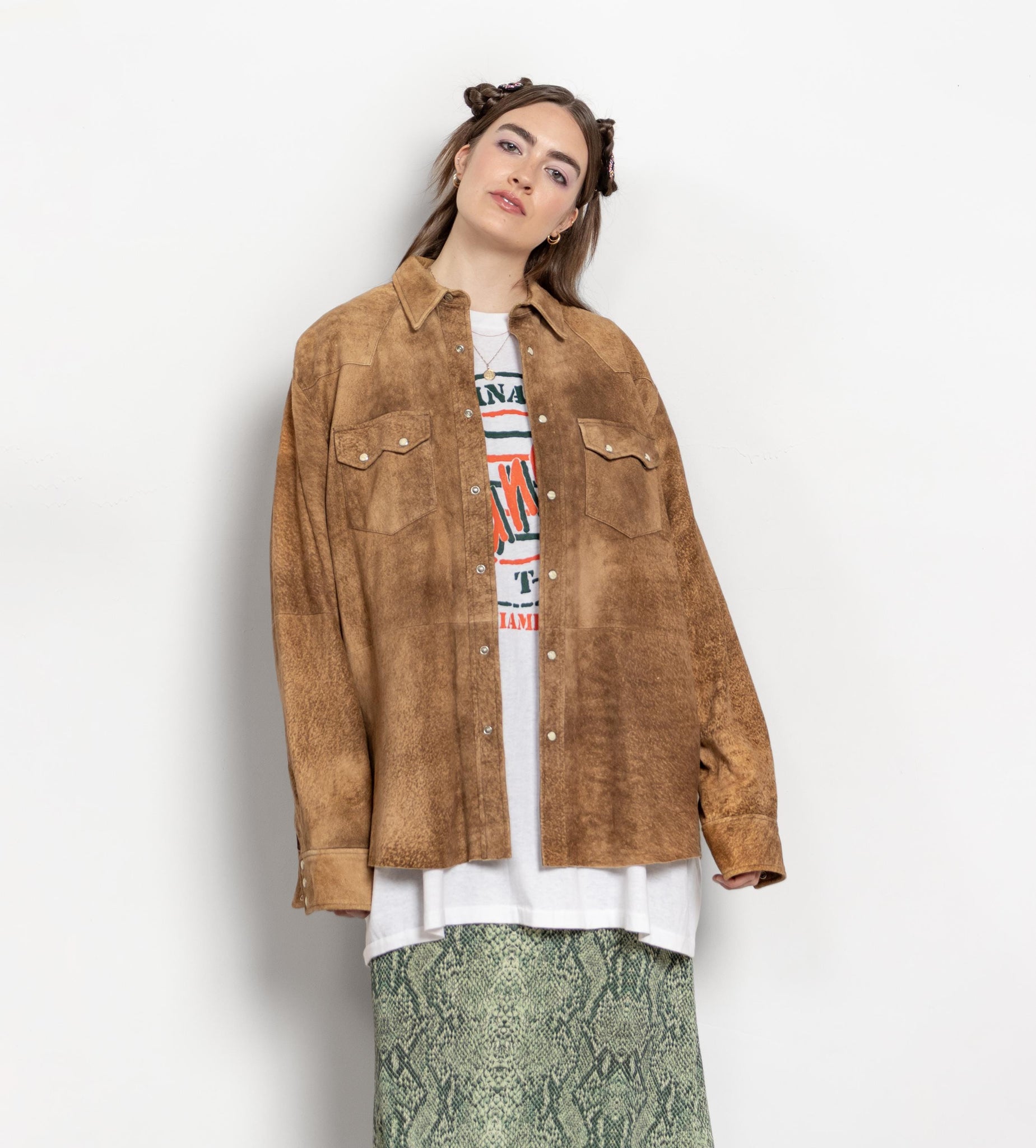 Person wearing a brown suede jacket over a graphic t-shirt on a white background