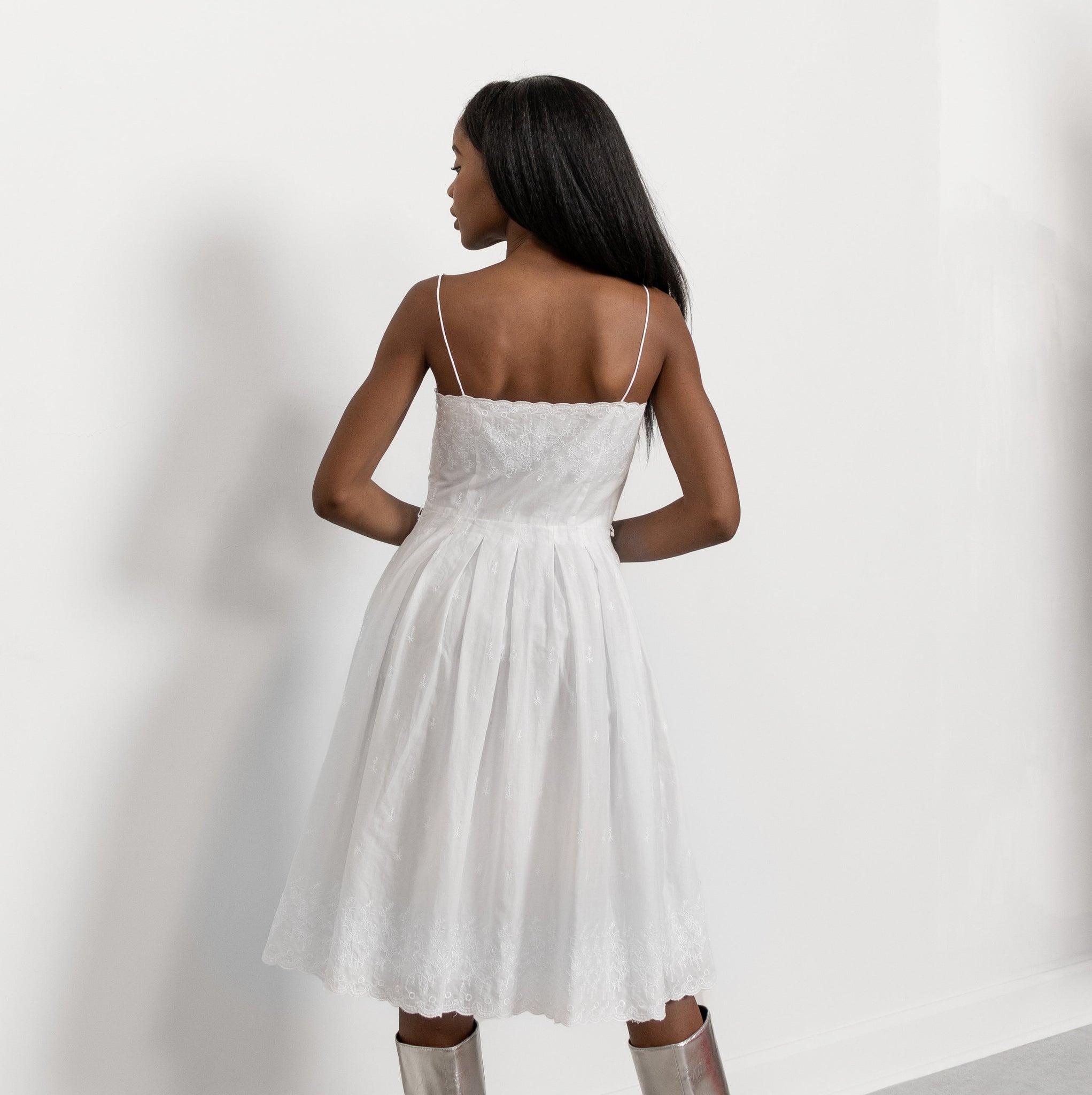 Woman wearing a white dress with thin straps on a plain background