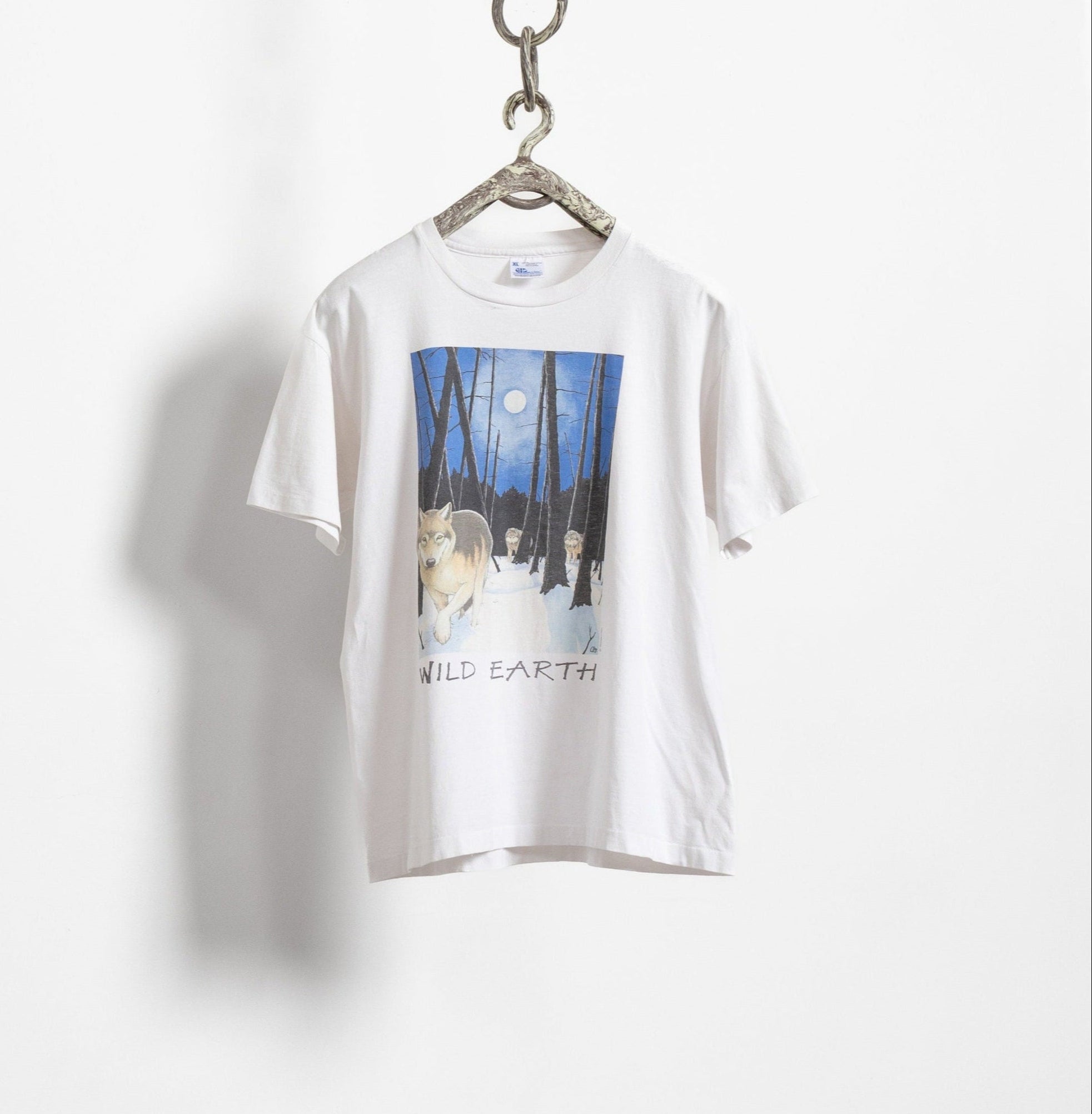Vintage white crew neck t-shirt with a graphic print of a wolf and moon on the front, hanging against a plain background.