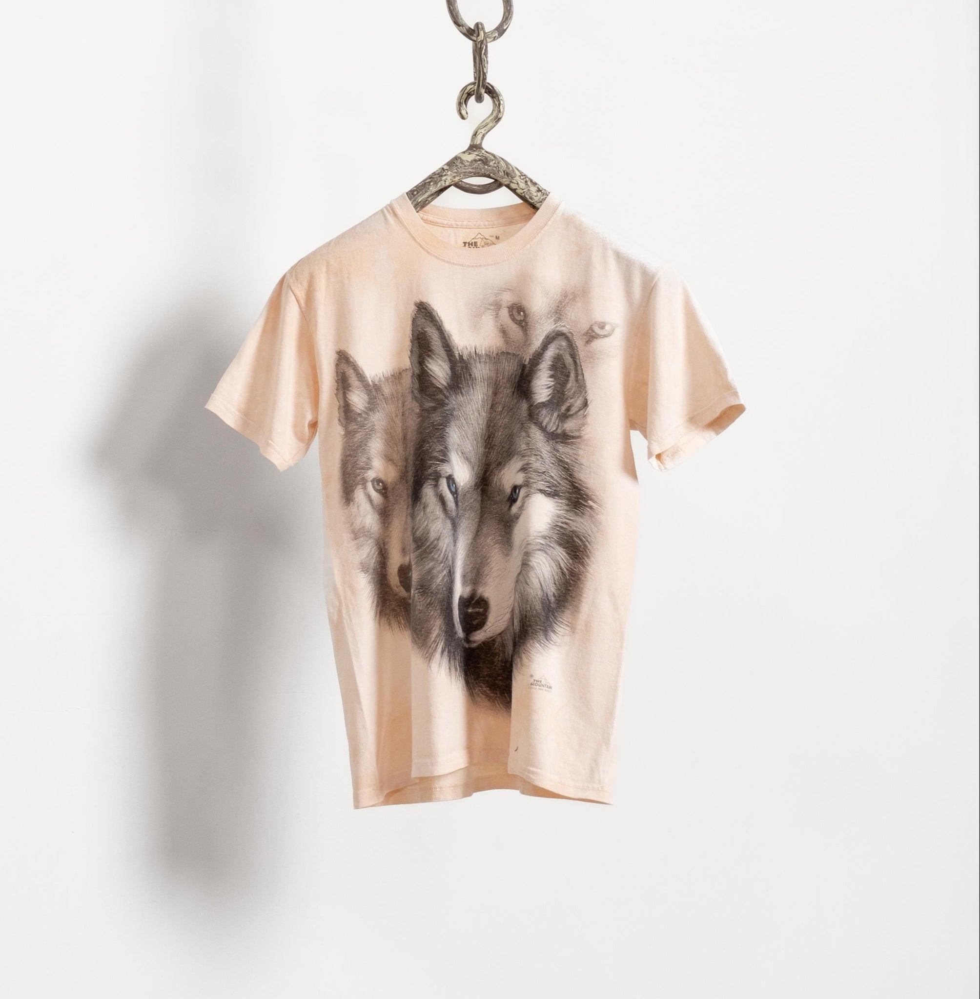 T-shirt with wolf design on a hanger against a white background