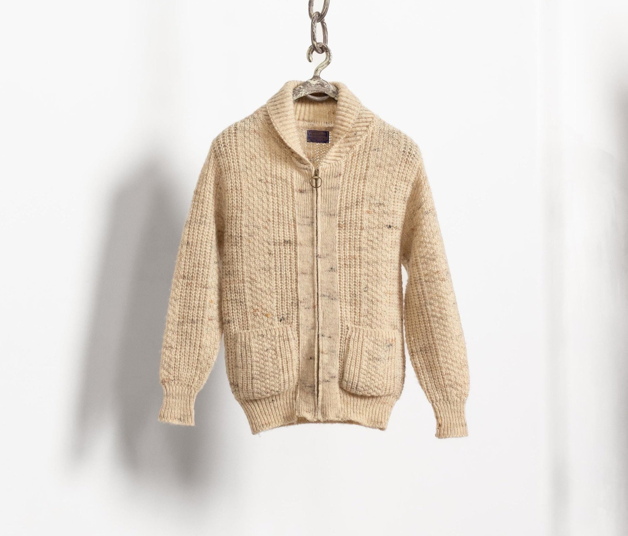 Beige zip-up sweater on a hanger against a white background