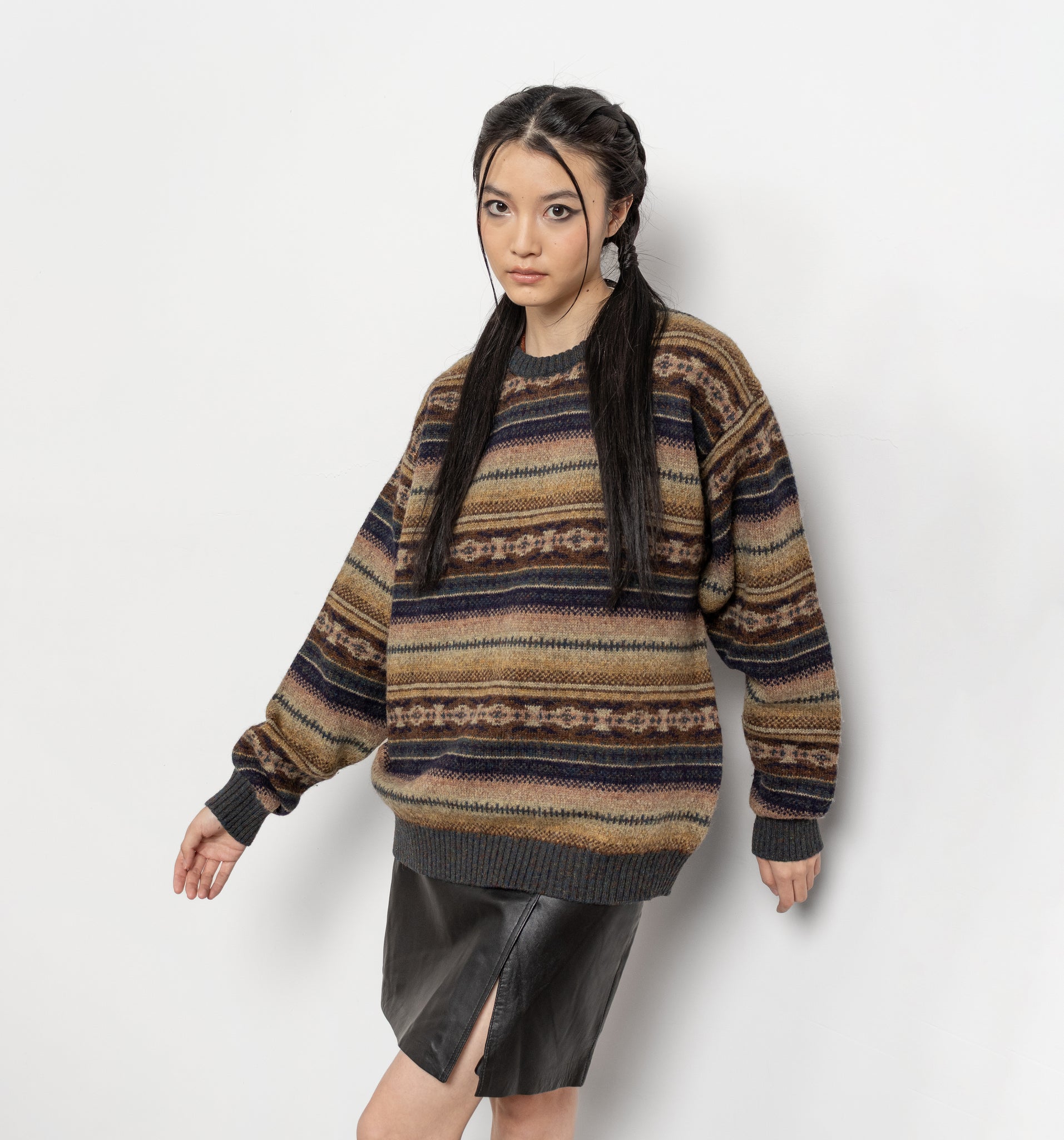 Woman wearing a patterned sweater and black skirt on a white background