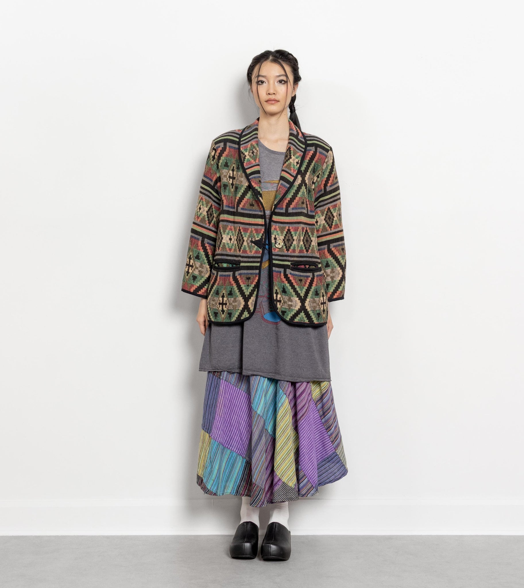 Person wearing a colorful patterned coat and skirt on a white background