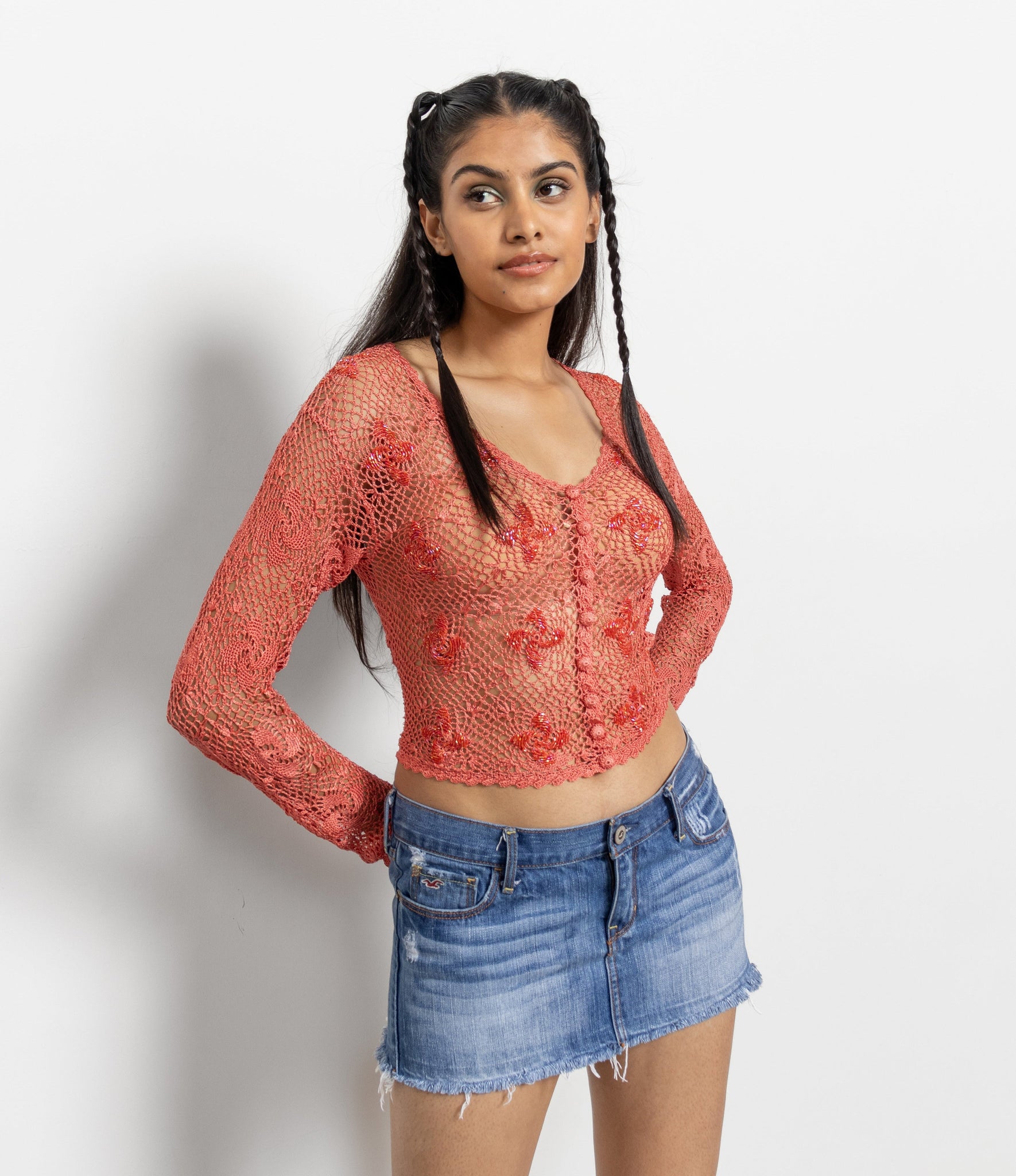 A woman wearing a red patterned top and a blue denim mini skirt with a raw hem.