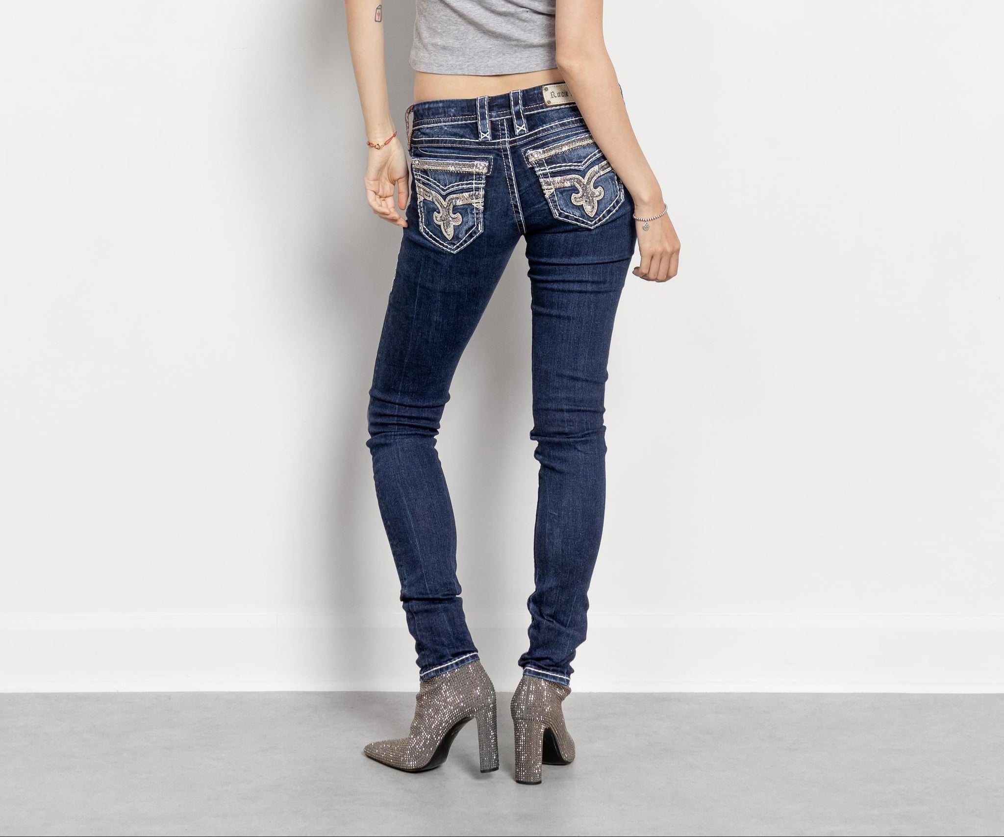 Woman wearing blue jeans and a gray top on a white background