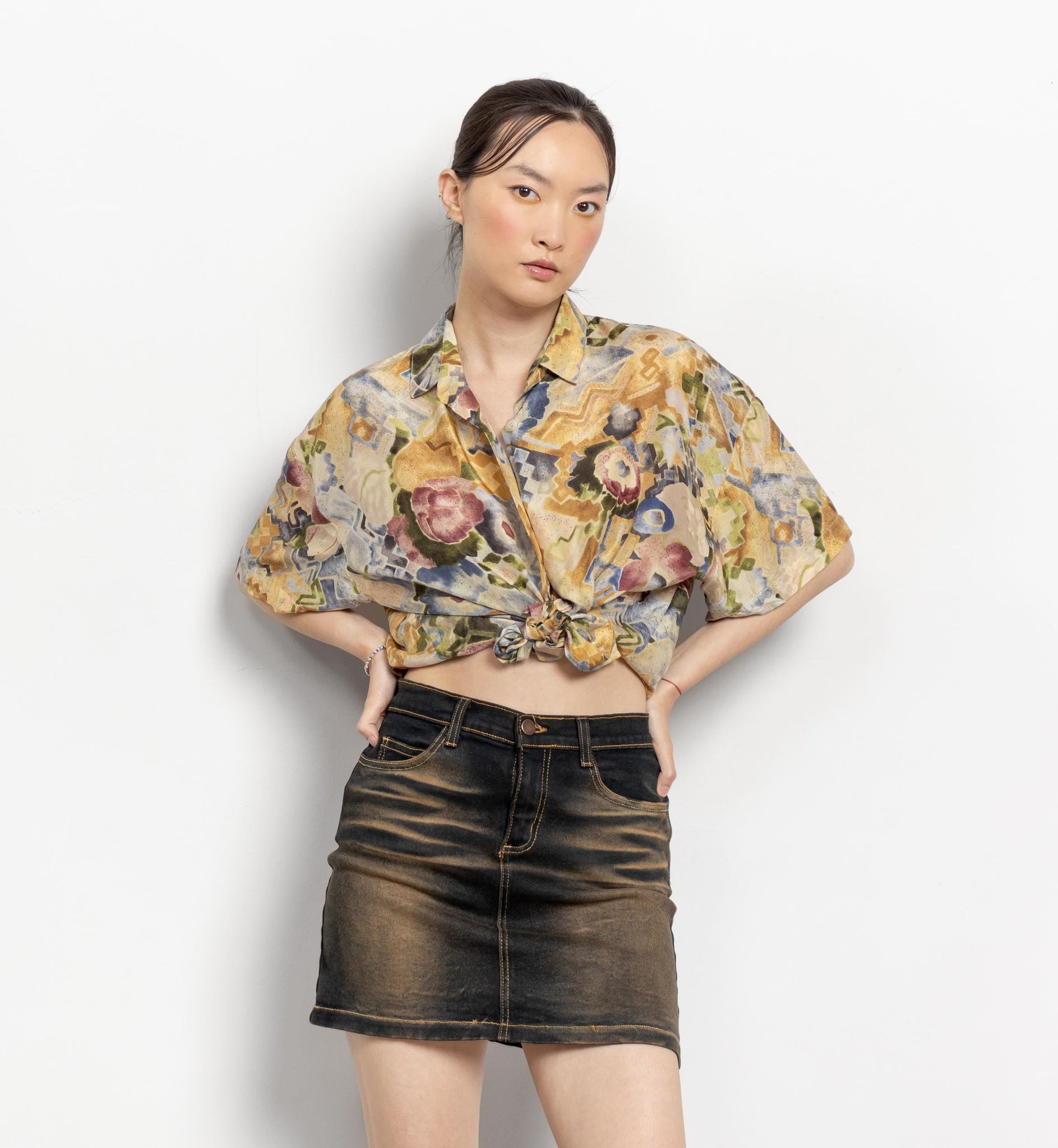 Woman wearing a floral blouse and black skirt on a white background