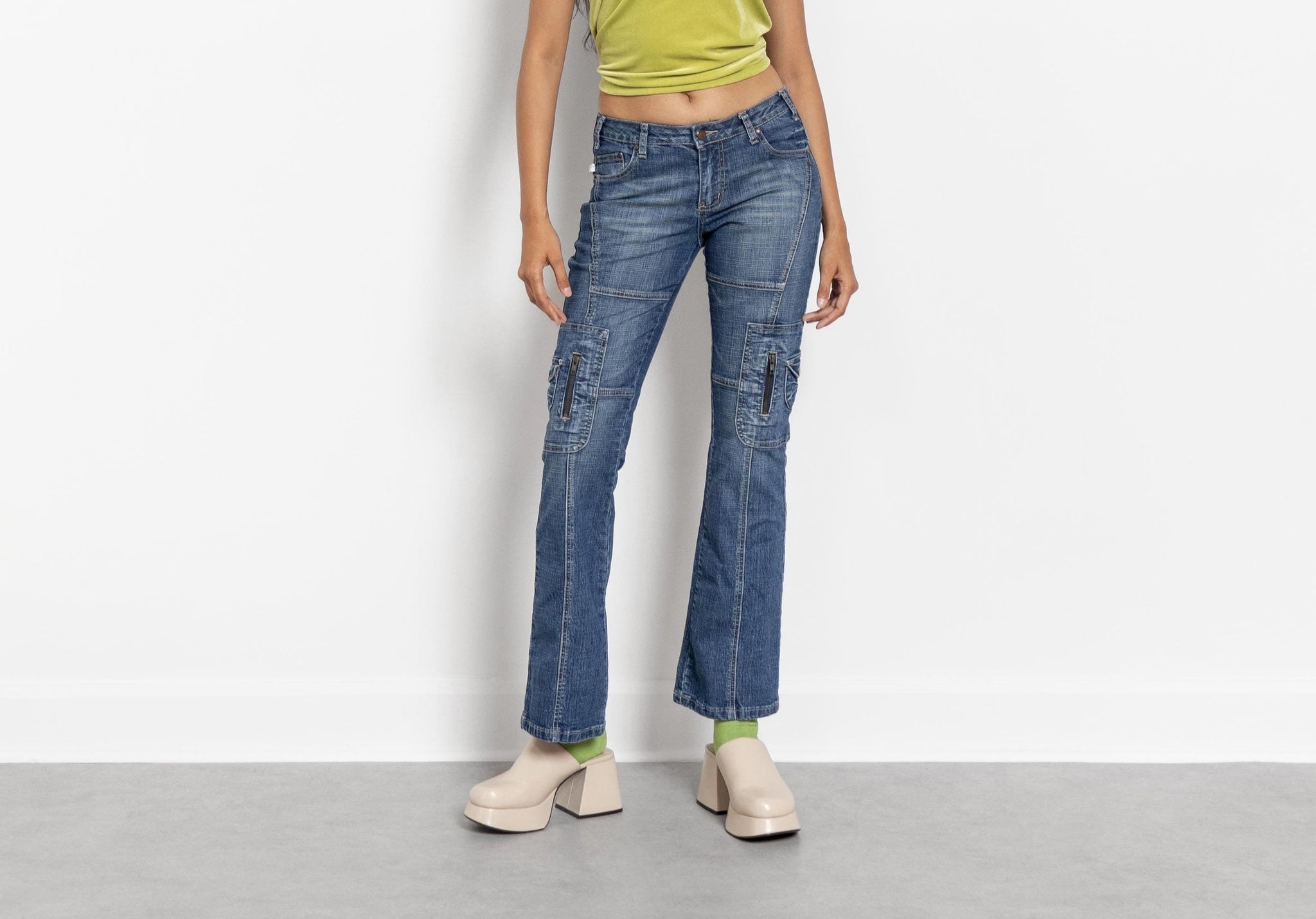 A person wearing low rise Y2K denim jeans with side cargo pockets, standing against a plain background.