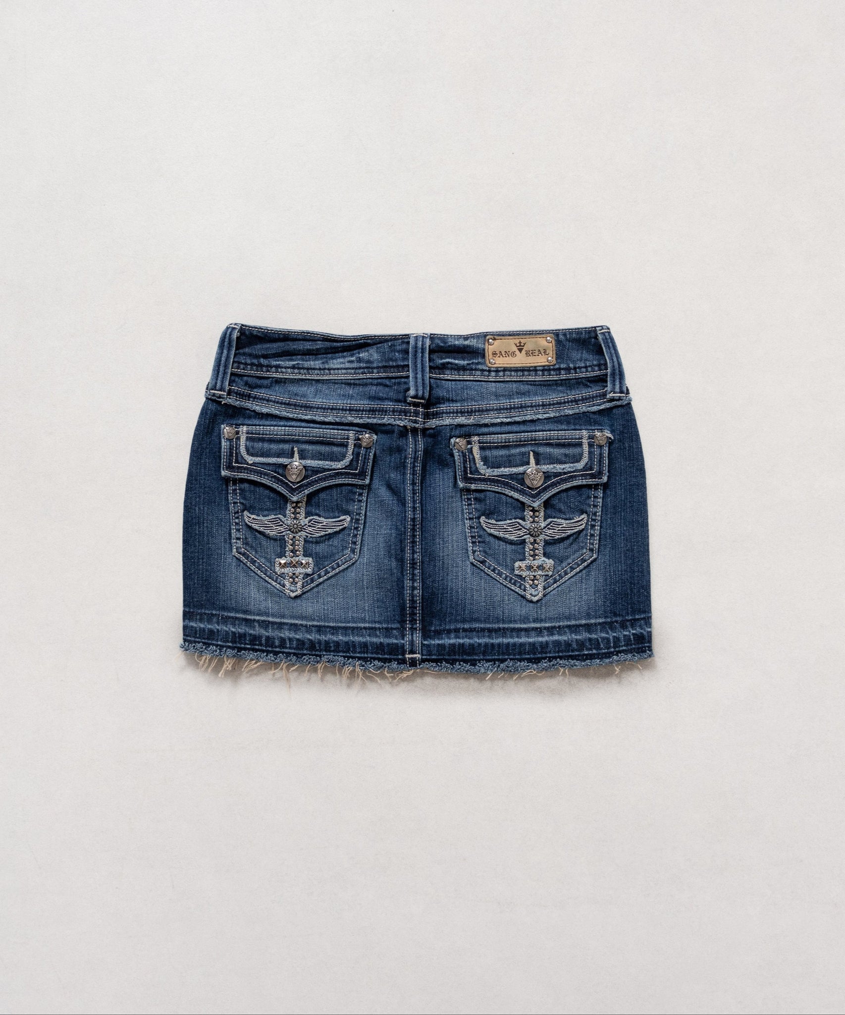 A low-rise denim mini skirt with studded detailing and faux fur lining at the hem.