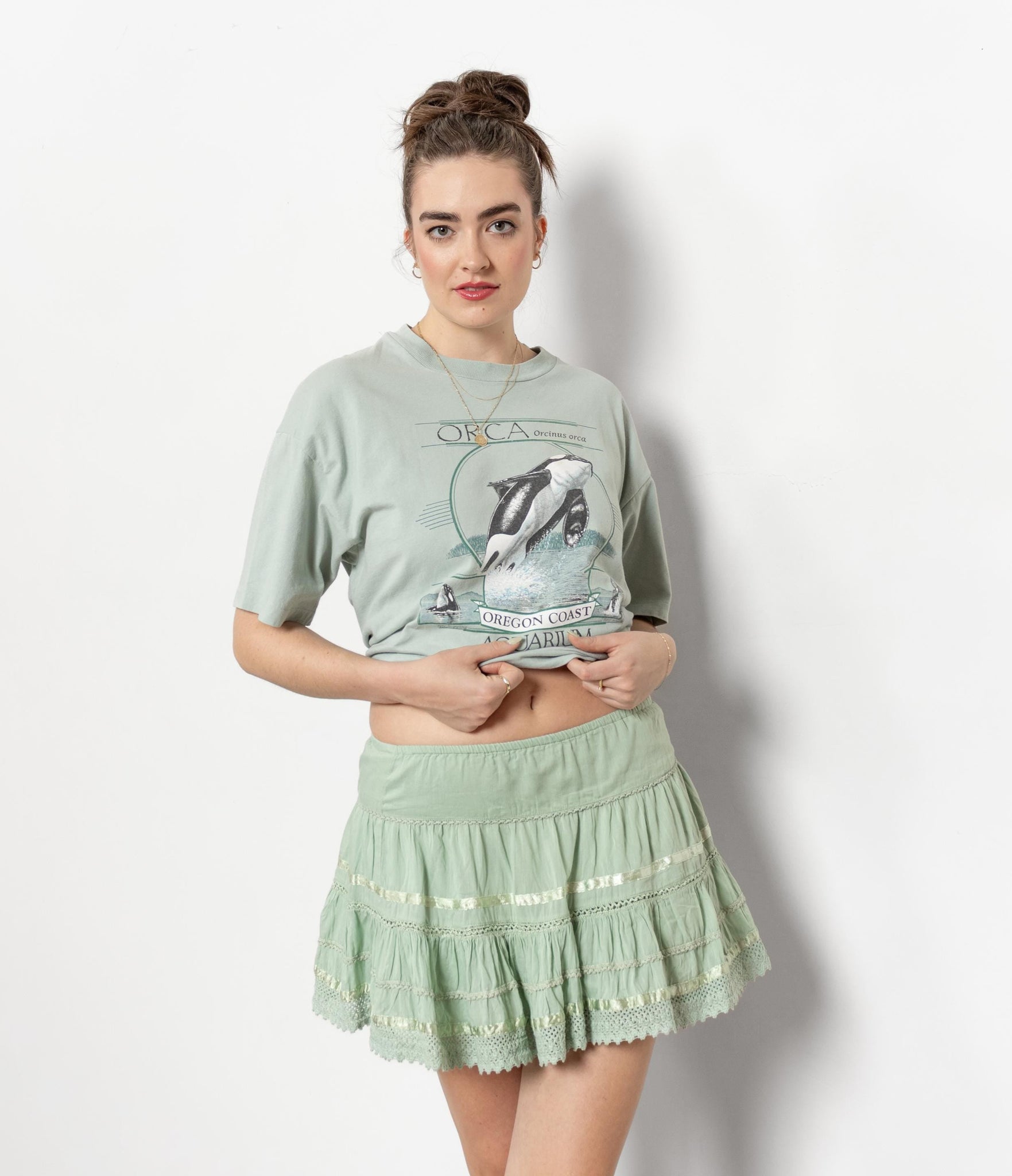 Woman wearing a green graphic t-shirt and skirt against a white background