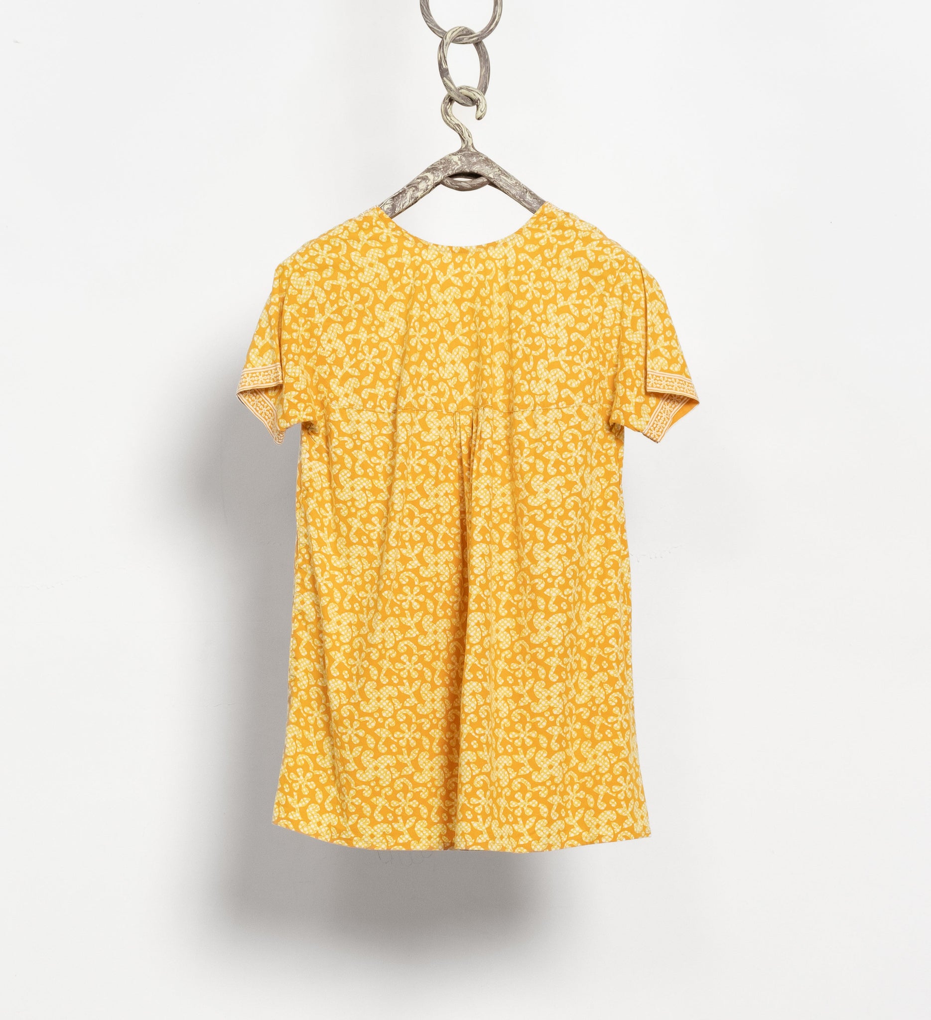 Yellow floral dress on a hanger against a white background