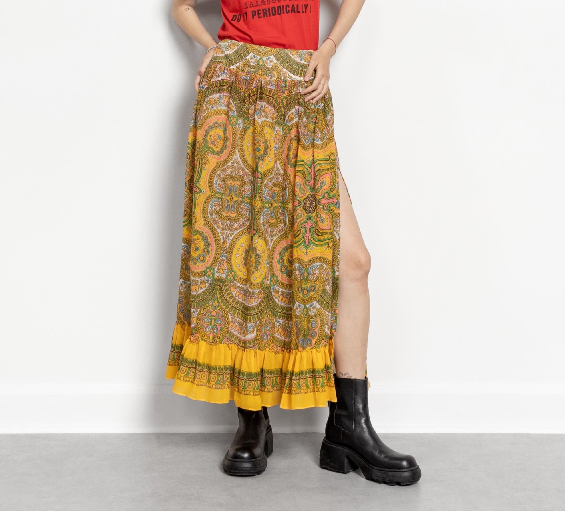 Woman wearing a red t-shirt and patterned yellow skirt on a white background