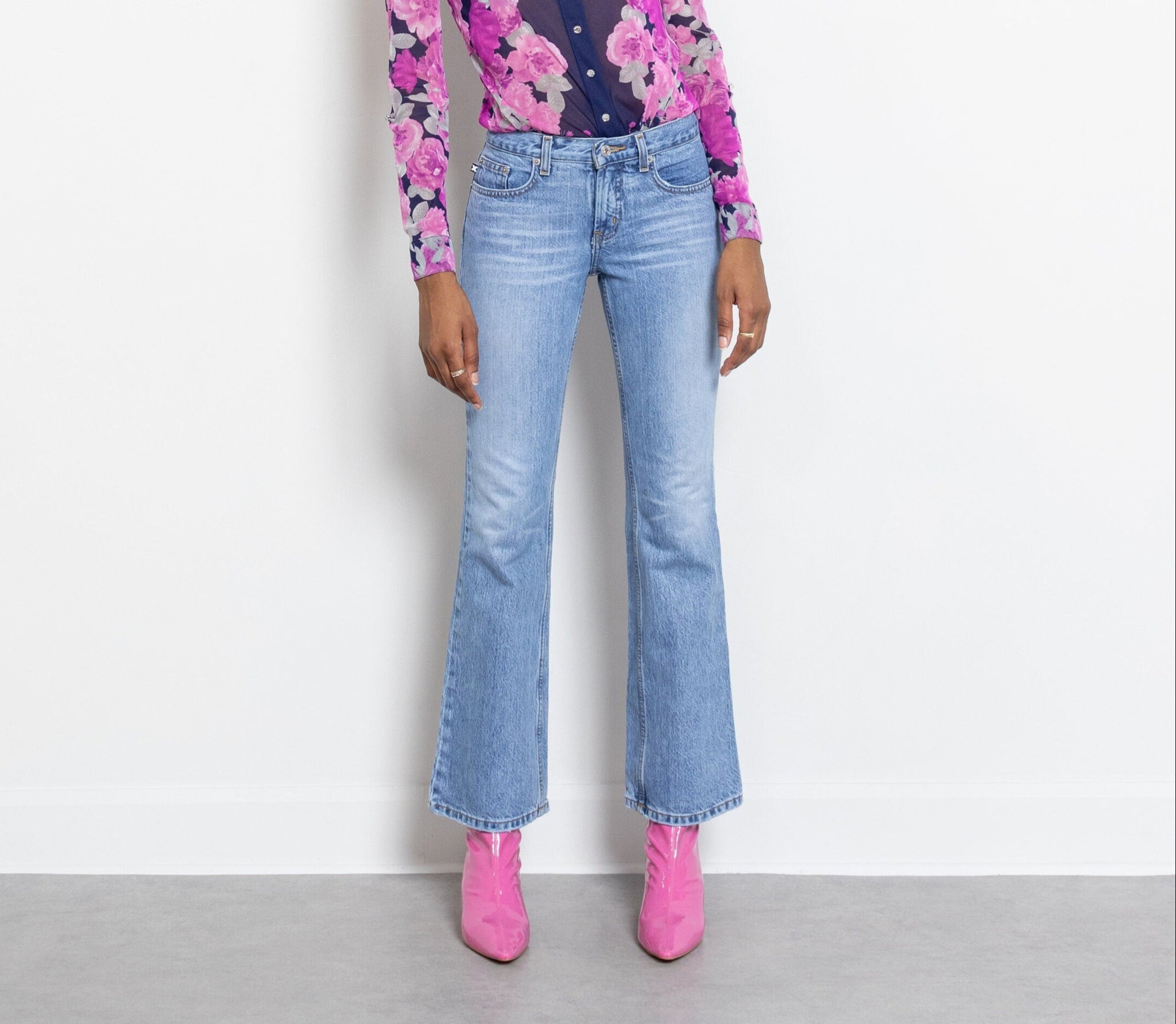 A pair of low rise flared hem jeans with a zip fly. The jeans are faded with a slim fit and a slight bell bottom leg.