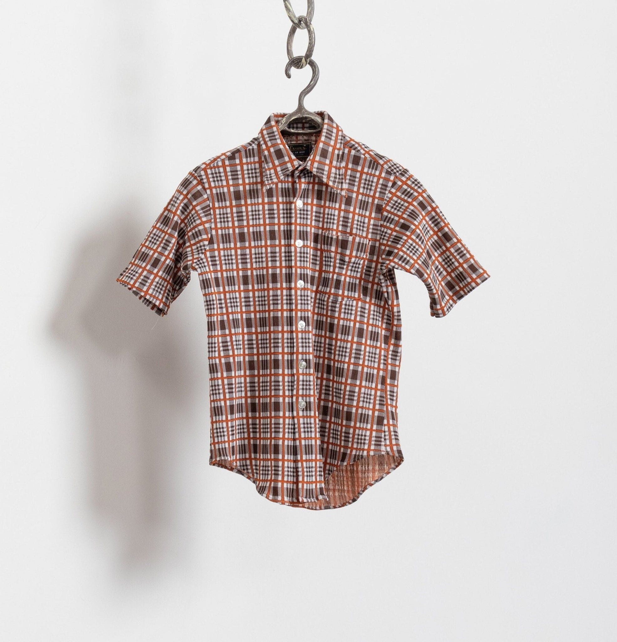 Plaid shirt hanging on a hook against a white background