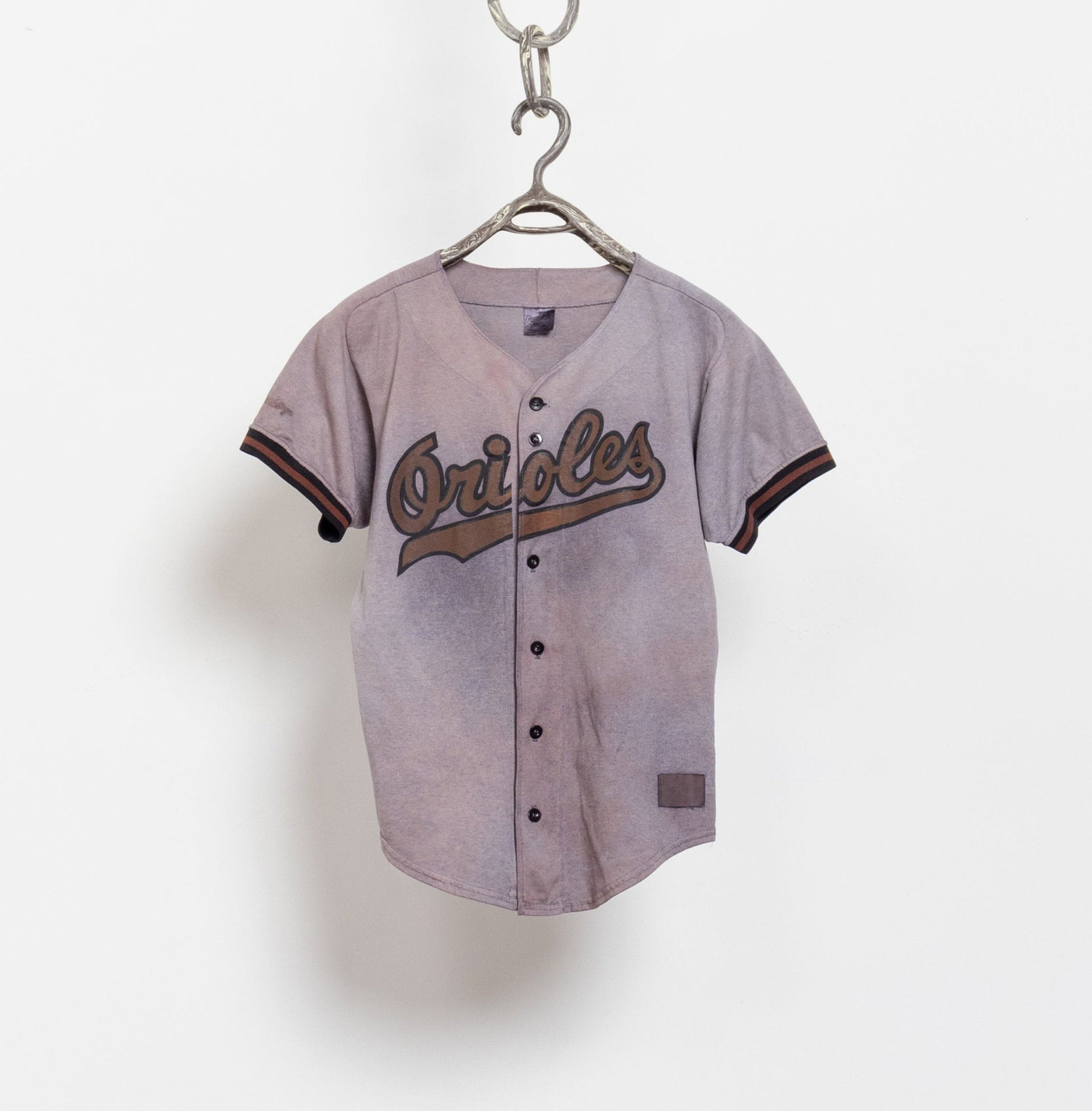 A vintage Orioles button-up poly cotton baseball tee in brown with team number 21 on the back, hanging on a white background.