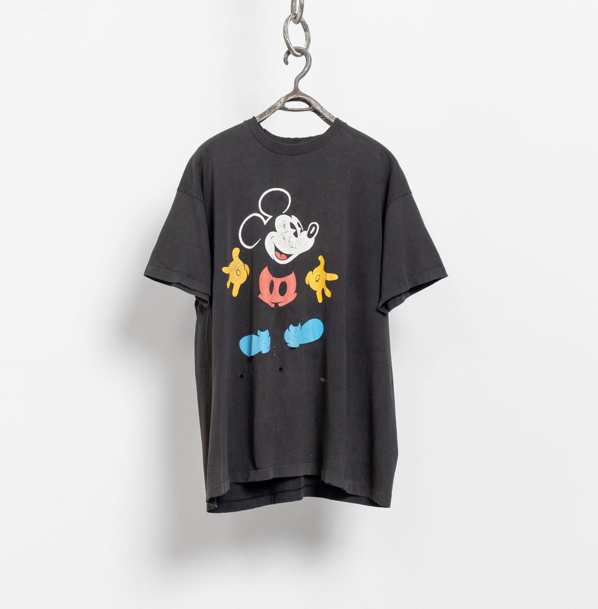 Vintage 90's Mickey Mouse official Disney graphic oversize tee in black with a colorful character design, hanging on a hanger against a white background.