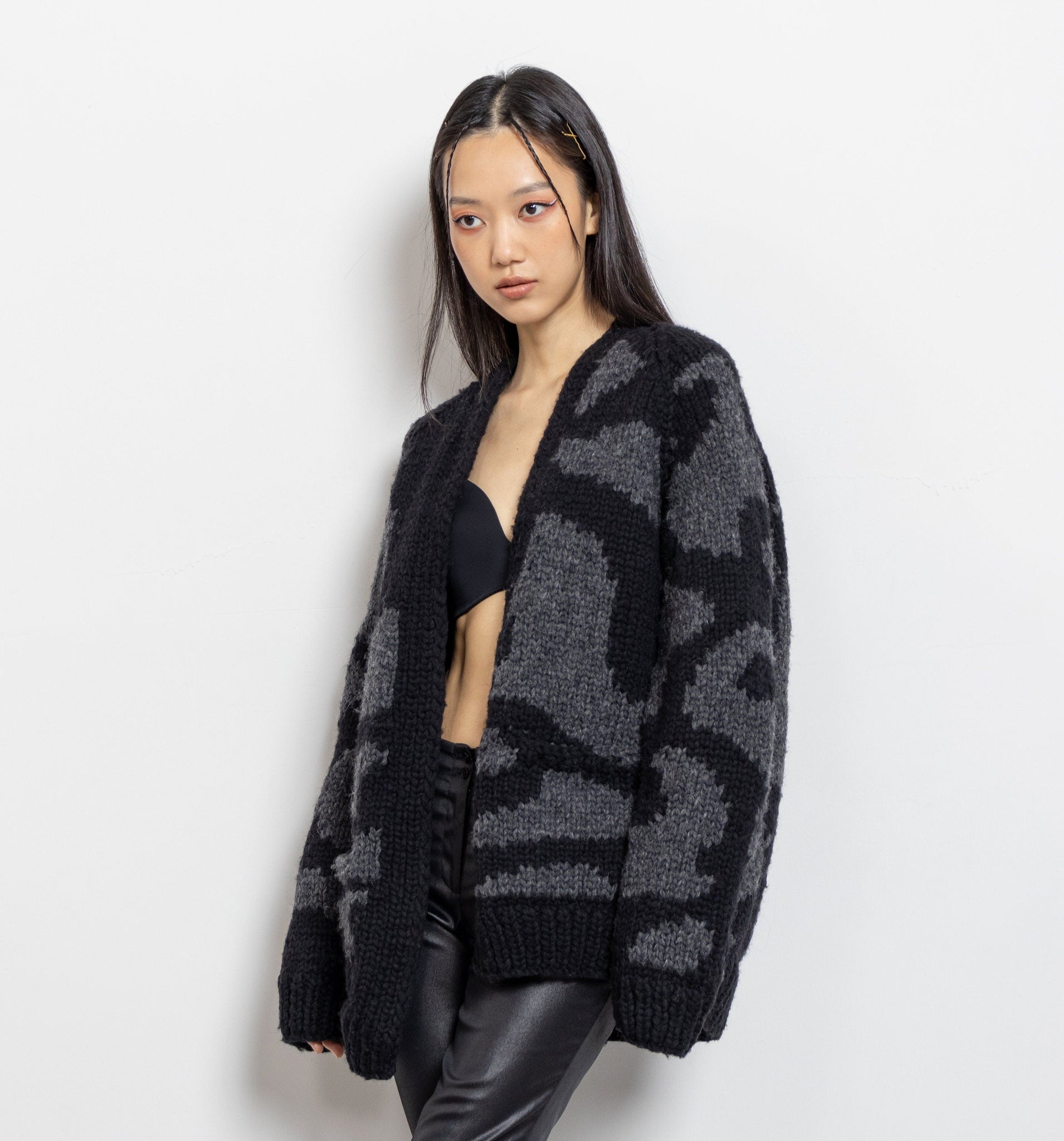 A person wearing a vintage 90's Maharishi brand geometric design cardigan in shades of dark and medium grey, without buttons, and a thick, durable wool texture.