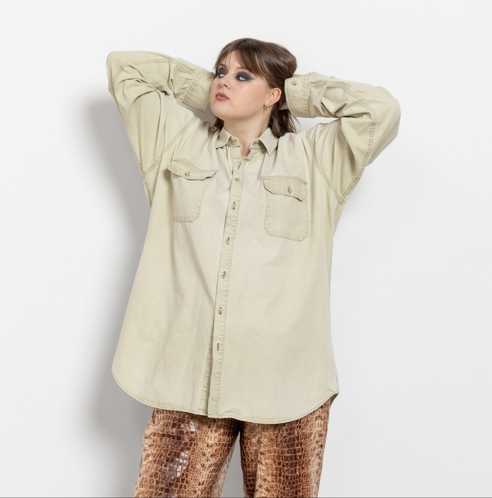 Person wearing a beige shirt and patterned pants on a white background