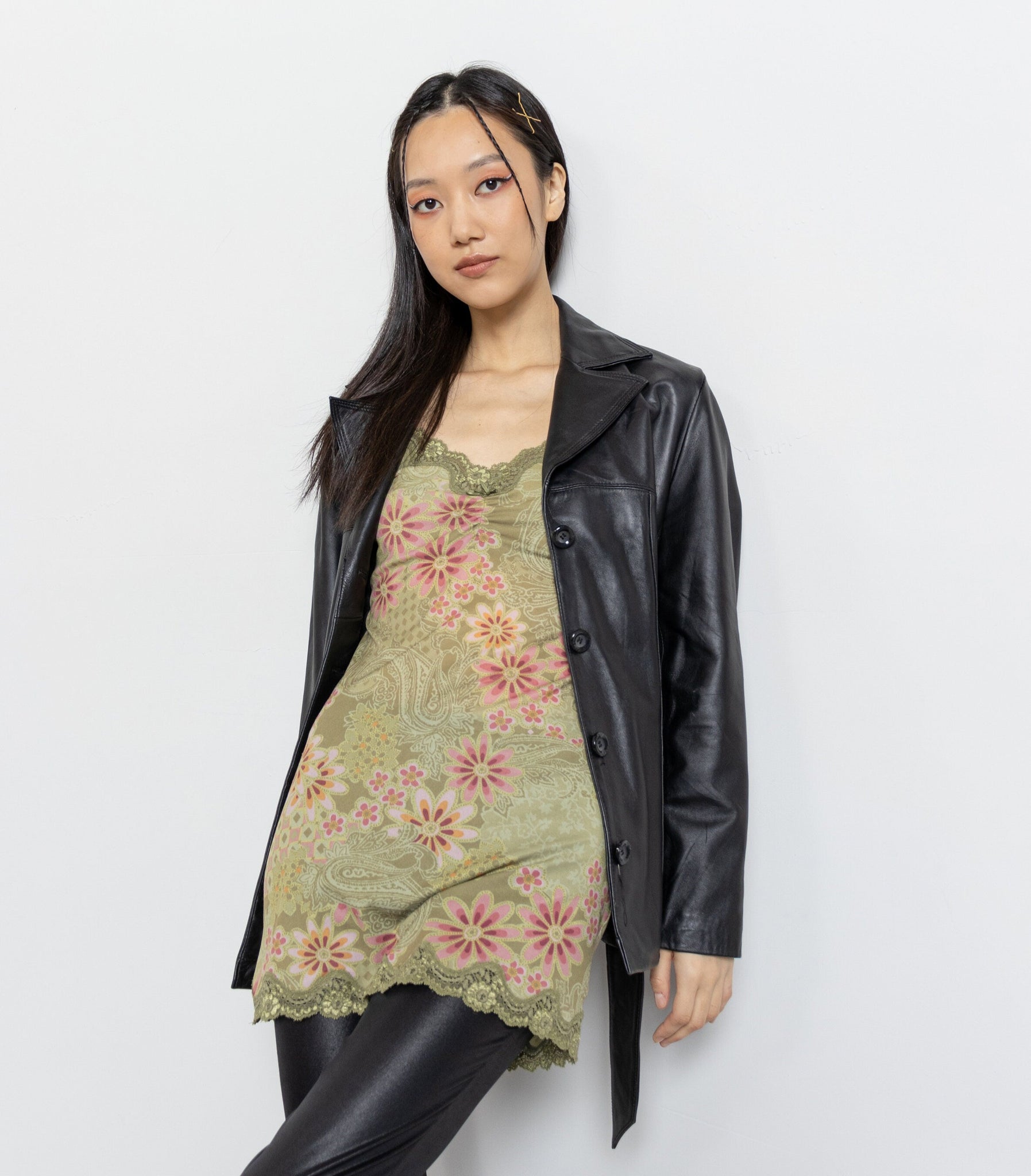 Woman wearing a floral dress under a black leather jacket on a white background