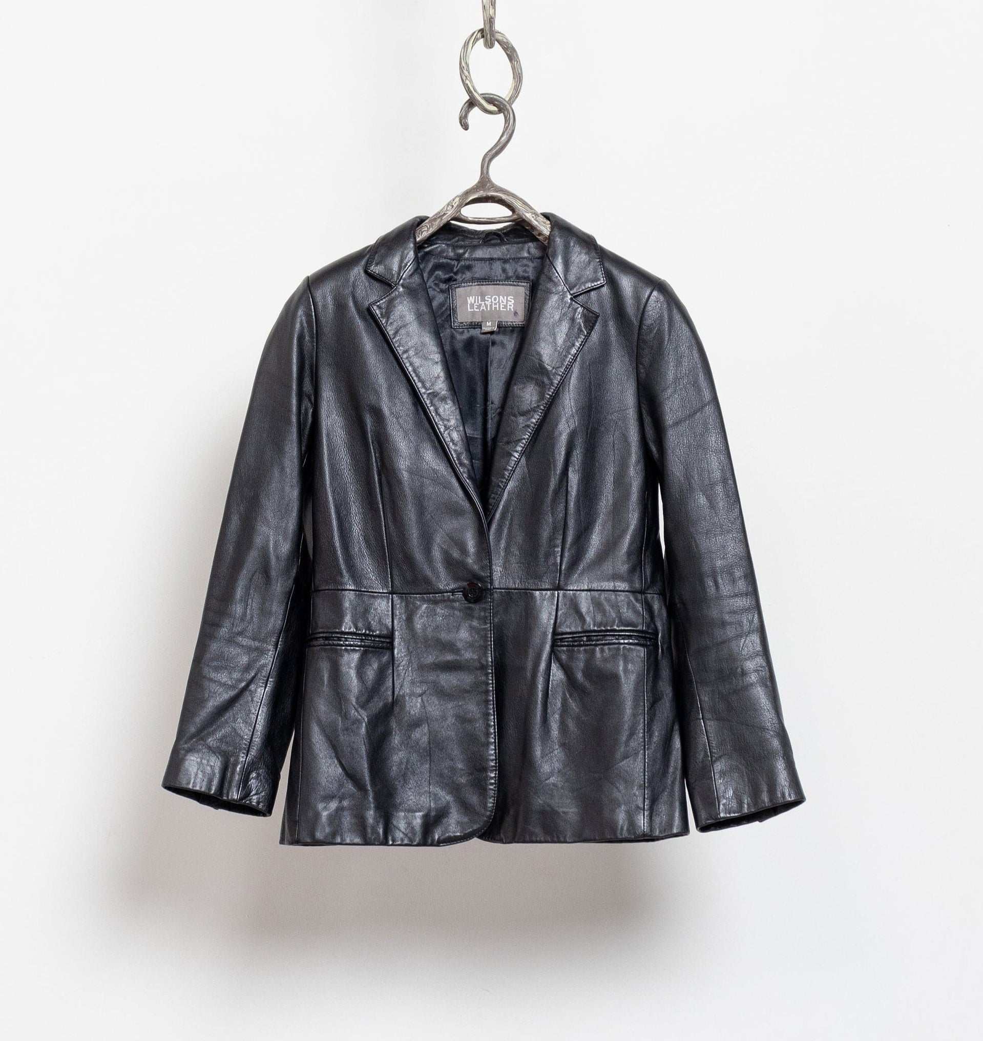 Black leather jacket on a hanger against a white background