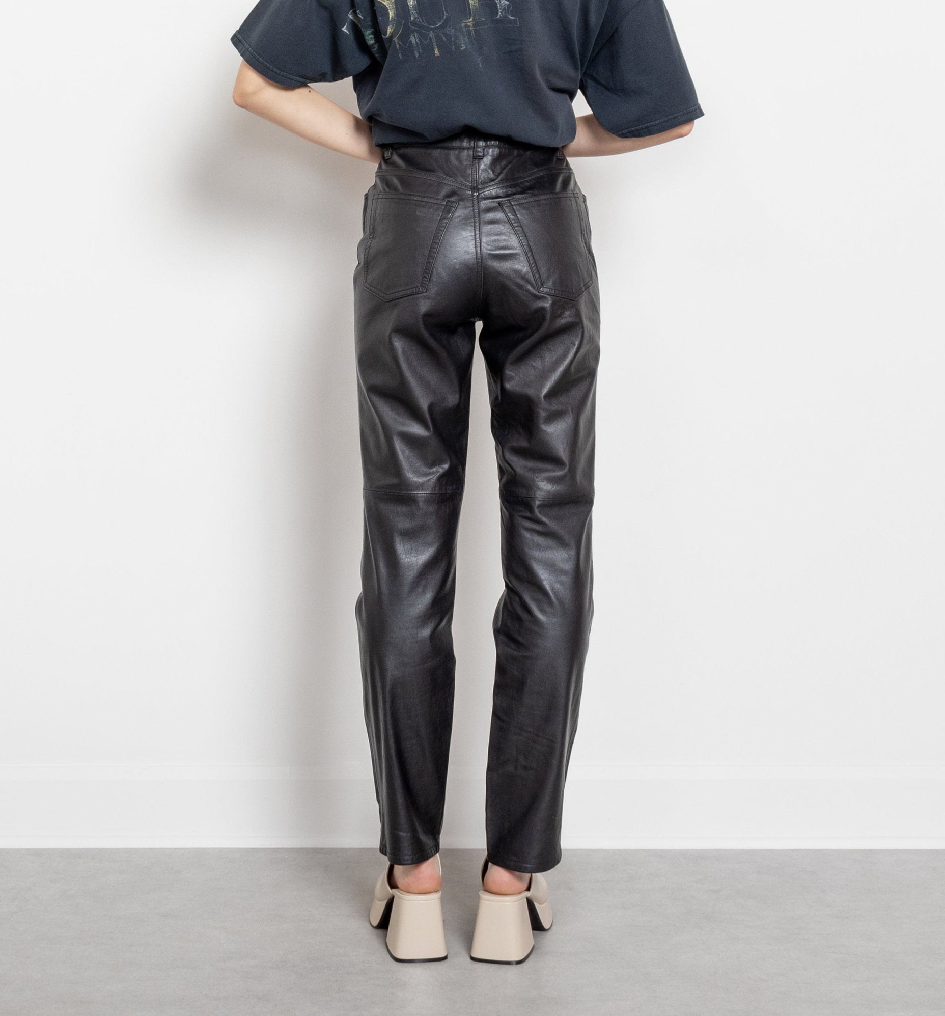 Person wearing a dark blue t-shirt and black leather pants against a white background