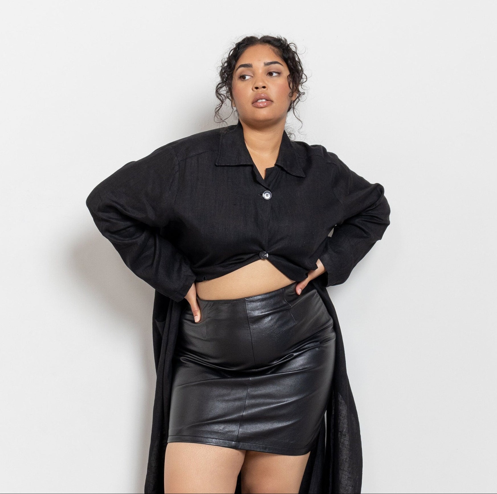 Person wearing a black outfit with a leather skirt against a white background