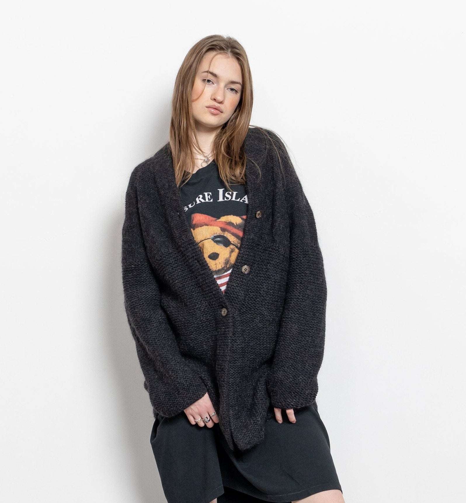 Person wearing a dark sweater, graphic t-shirt, and black knee-high boots against a white background