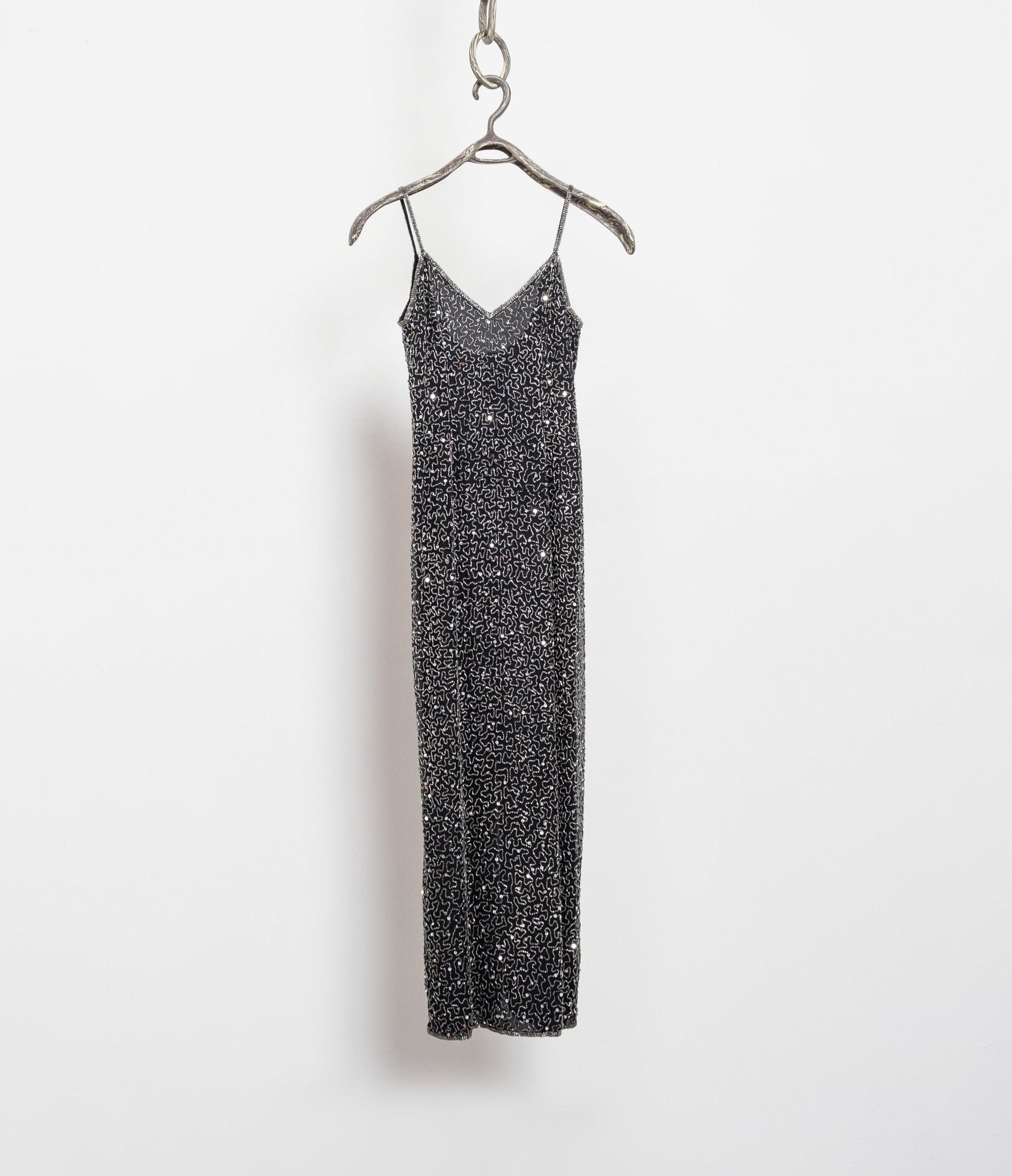 Black sequin dress on a hanger against a white background