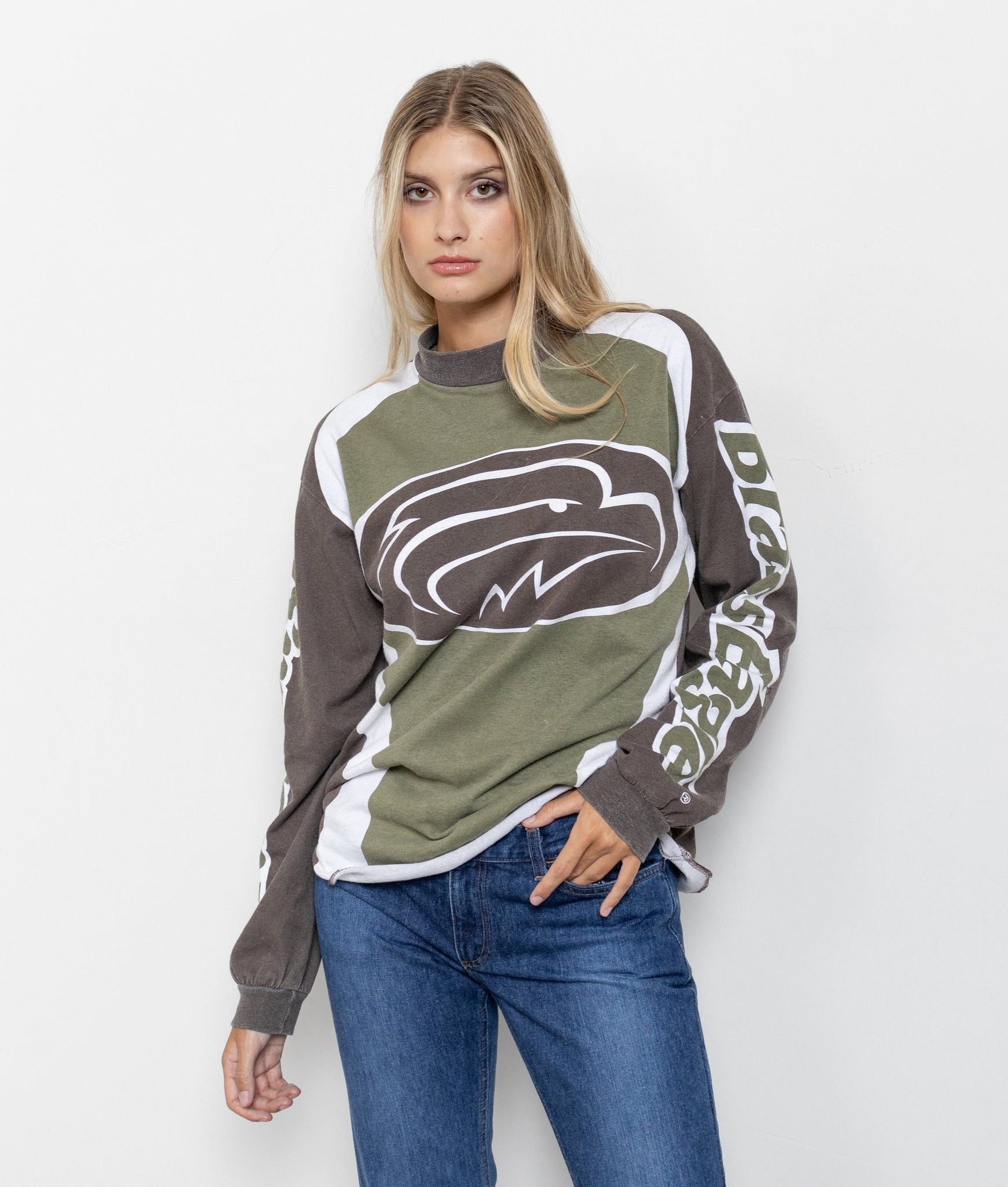 A person wearing a long sleeve vintage Brass Eagle t-shirt in green and brown with an oversized logo on the front.
