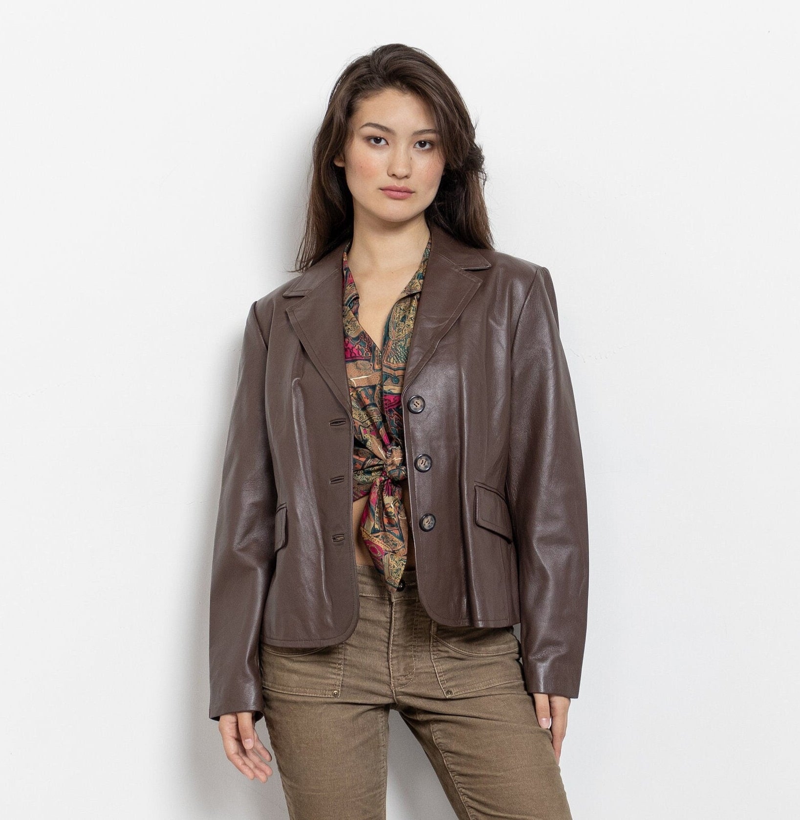 Woman wearing a brown leather jacket and brown pants on a white background