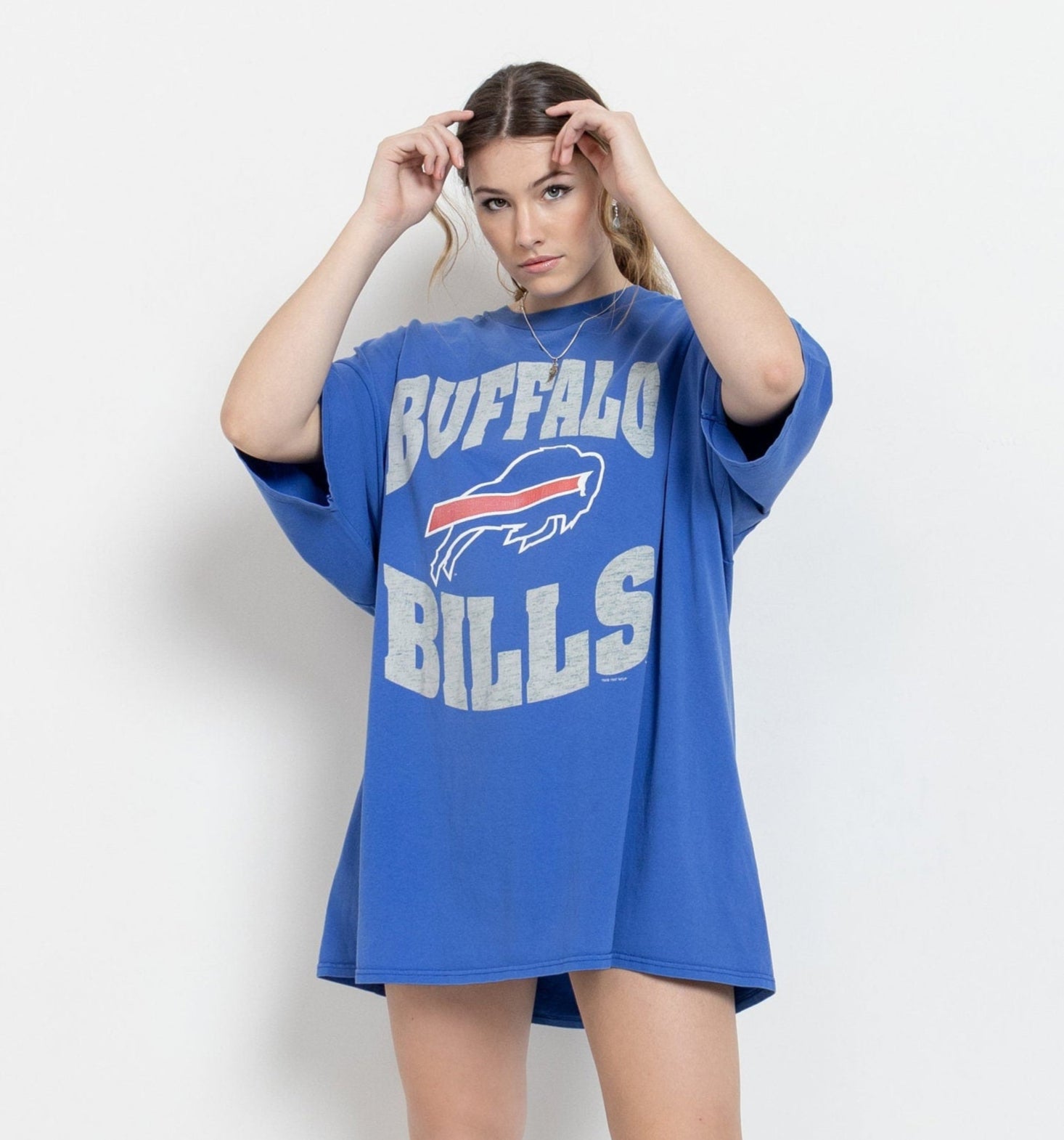 A person wearing an oversized blue Buffalo Bills t-shirt with a graphic print of the team's logo.