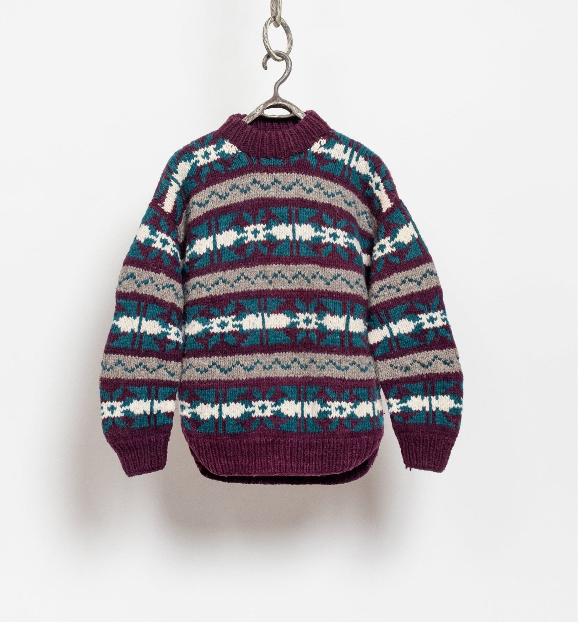 Patterned sweater on a hanger against a white background