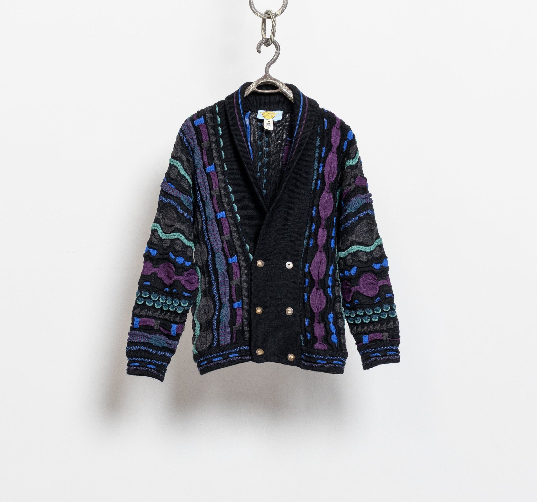 A vintage 90's patterned wool knit dad cardigan in hues of black, blue, green, and grey, displayed on a hanger against a white background.