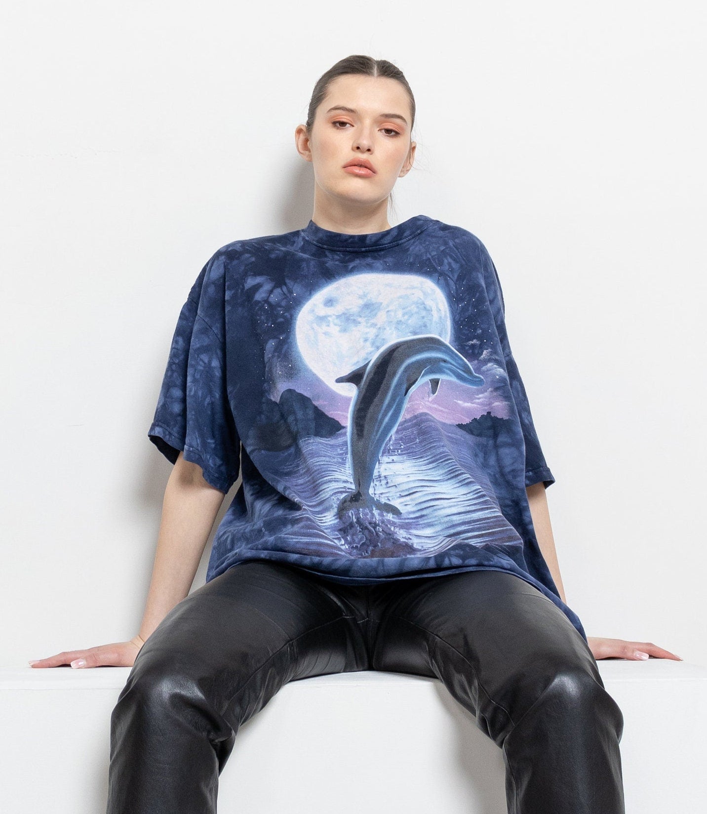 Person wearing a blue t-shirt with a dolphin design on a white background