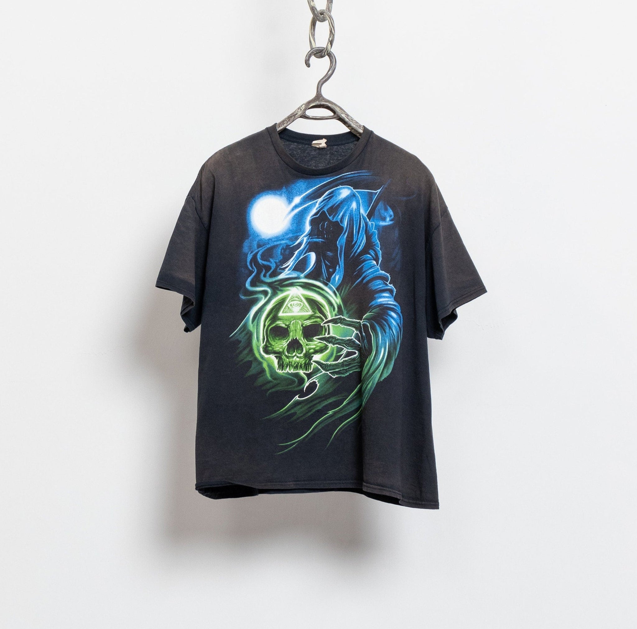 A black vintage t-shirt with a graphic of a skull and moon, and the text 'FASHION NIGHTMARES' displayed on a hanger against a white wall.
