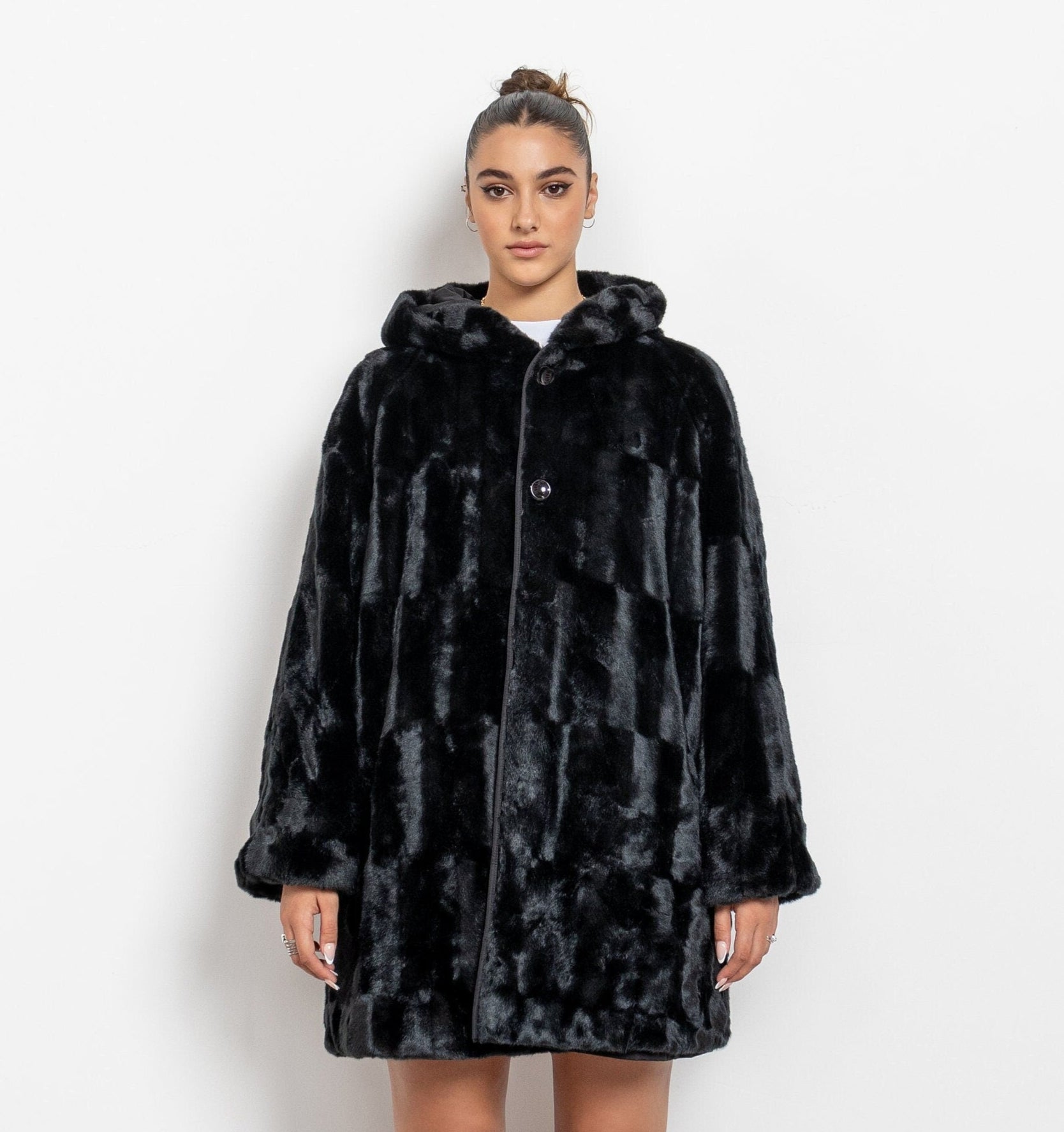 Person wearing a black faux fur coat and pink boots on a white background