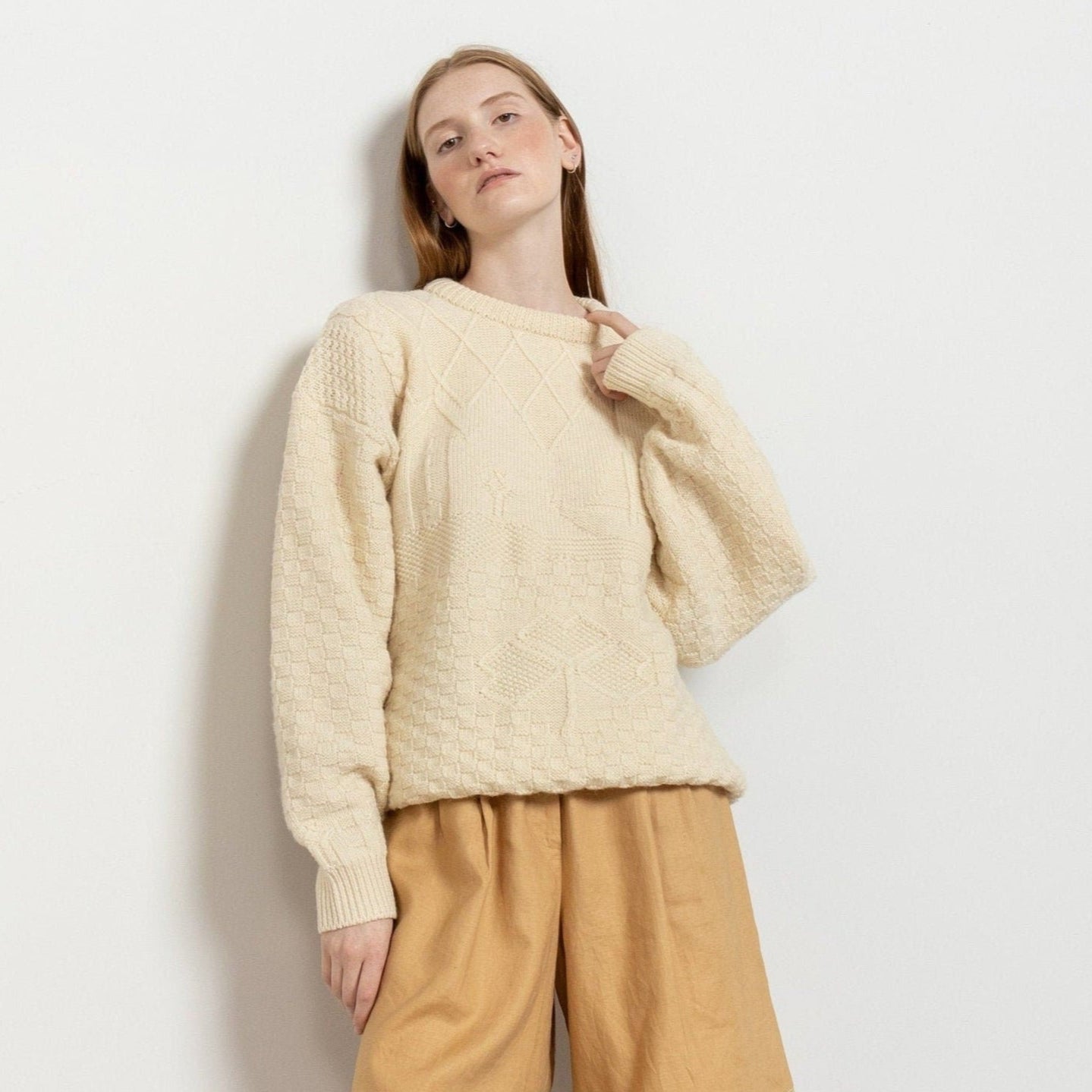 A model wearing a vintage 90's cream Irish wool cable knit pullover with a crew neck.