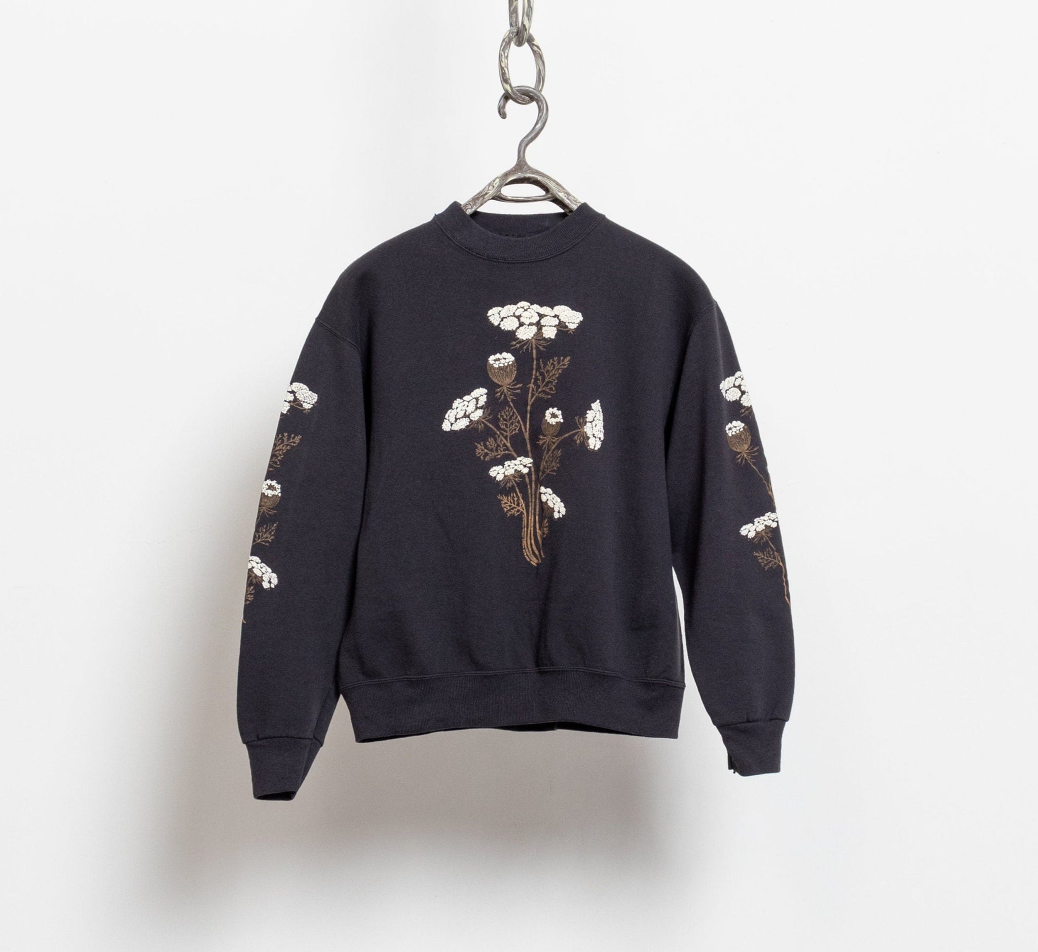 A black pullover sweatshirt with a floral print design, displayed on a hanger against a white background.
