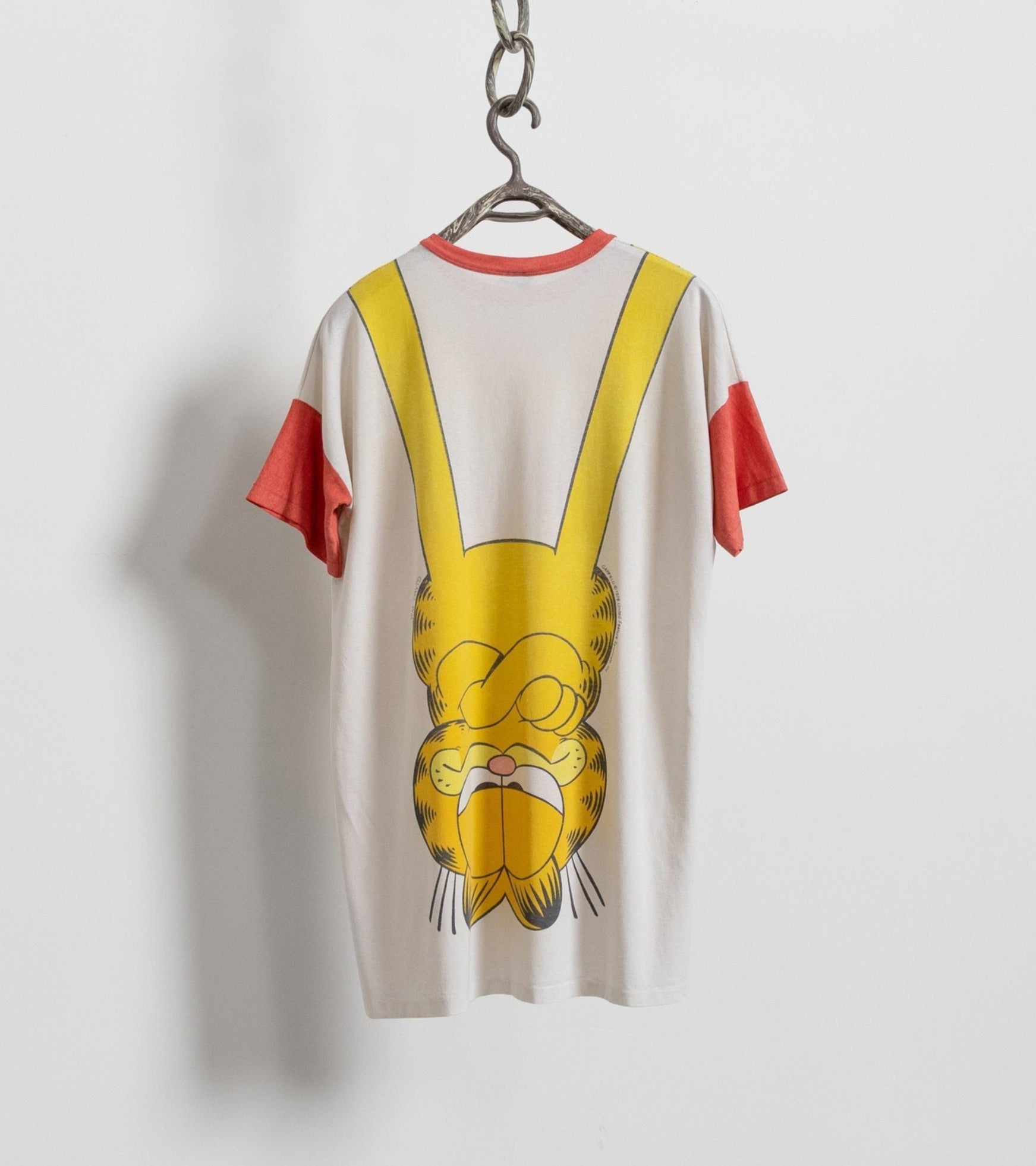 T-shirt with a cartoon character design on a hanger against a white background
