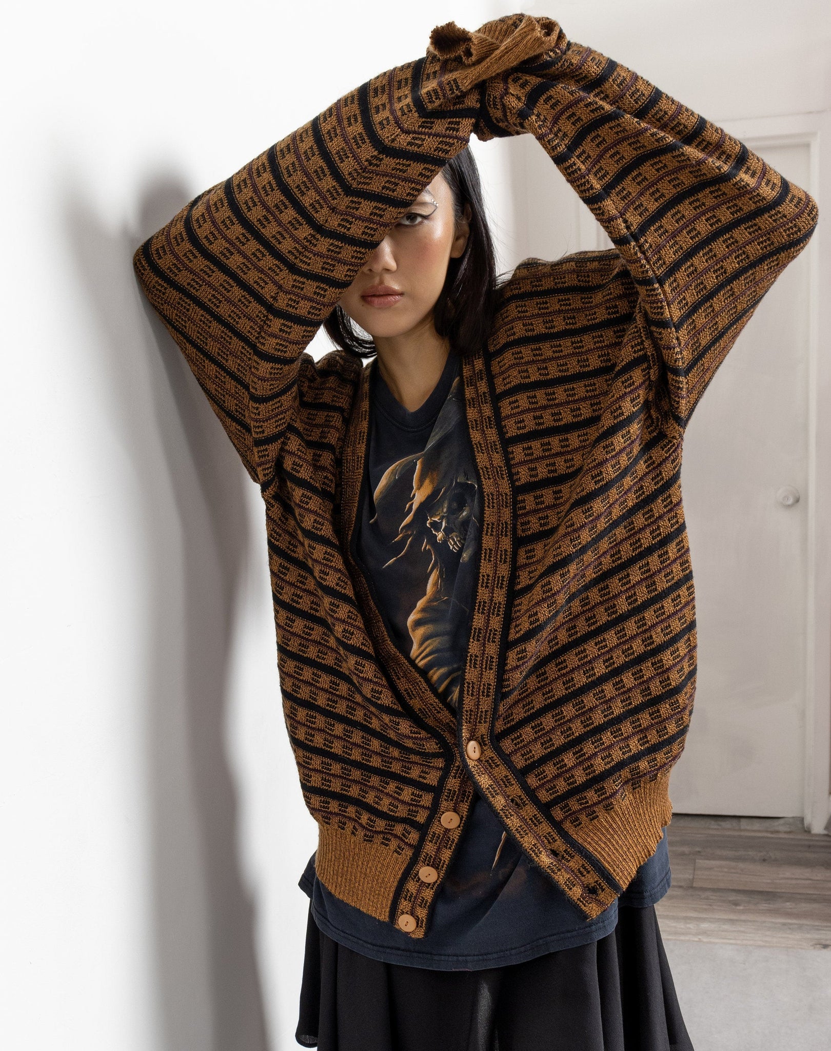 A person wearing a vintage 90's patterned 100% acrylic knit dad cardigan in a colorful striped pattern, with long sleeves, and a relaxed, oversized fit.