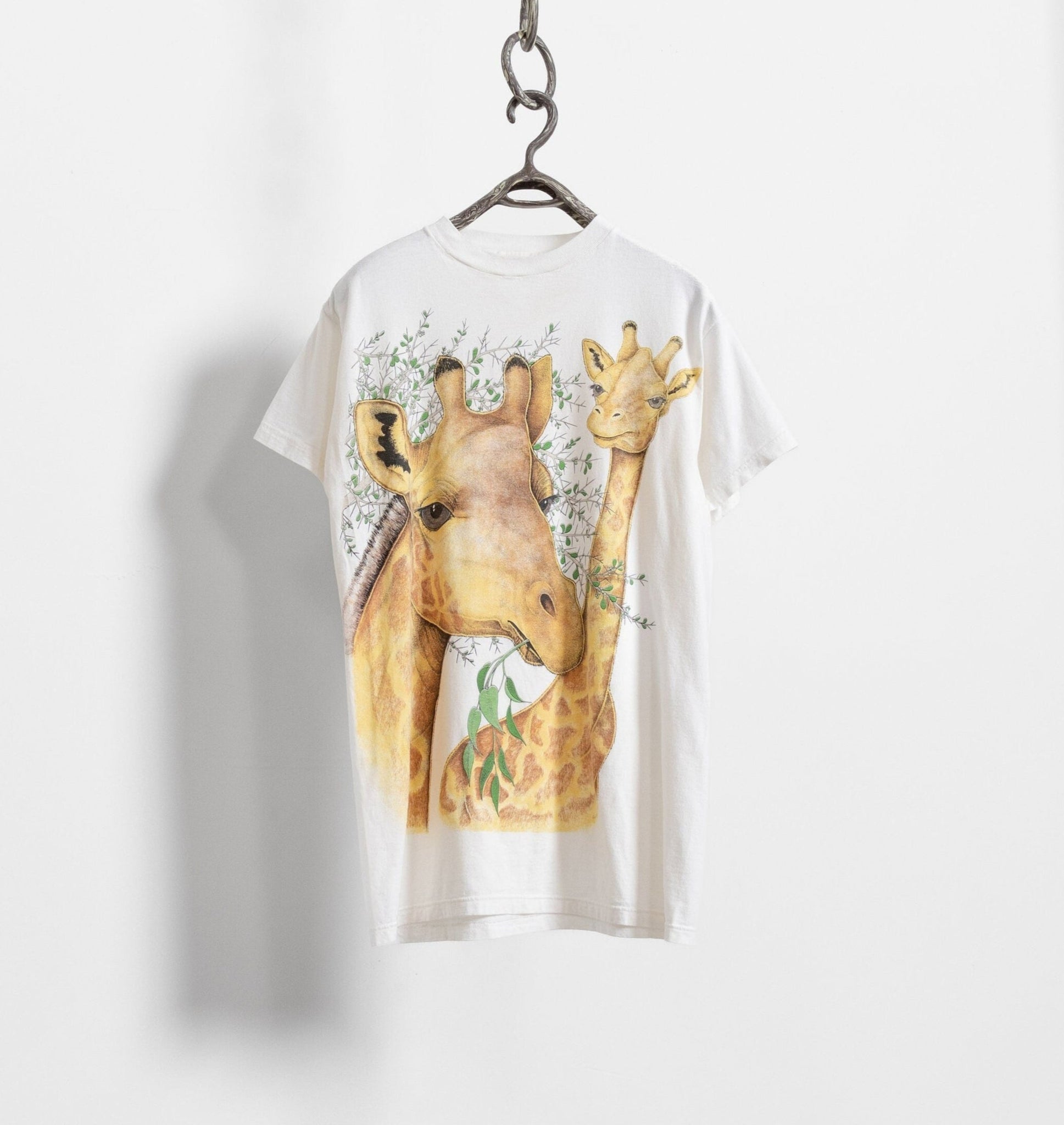 White t-shirt with a giraffe graphic on a hanger against a white background
