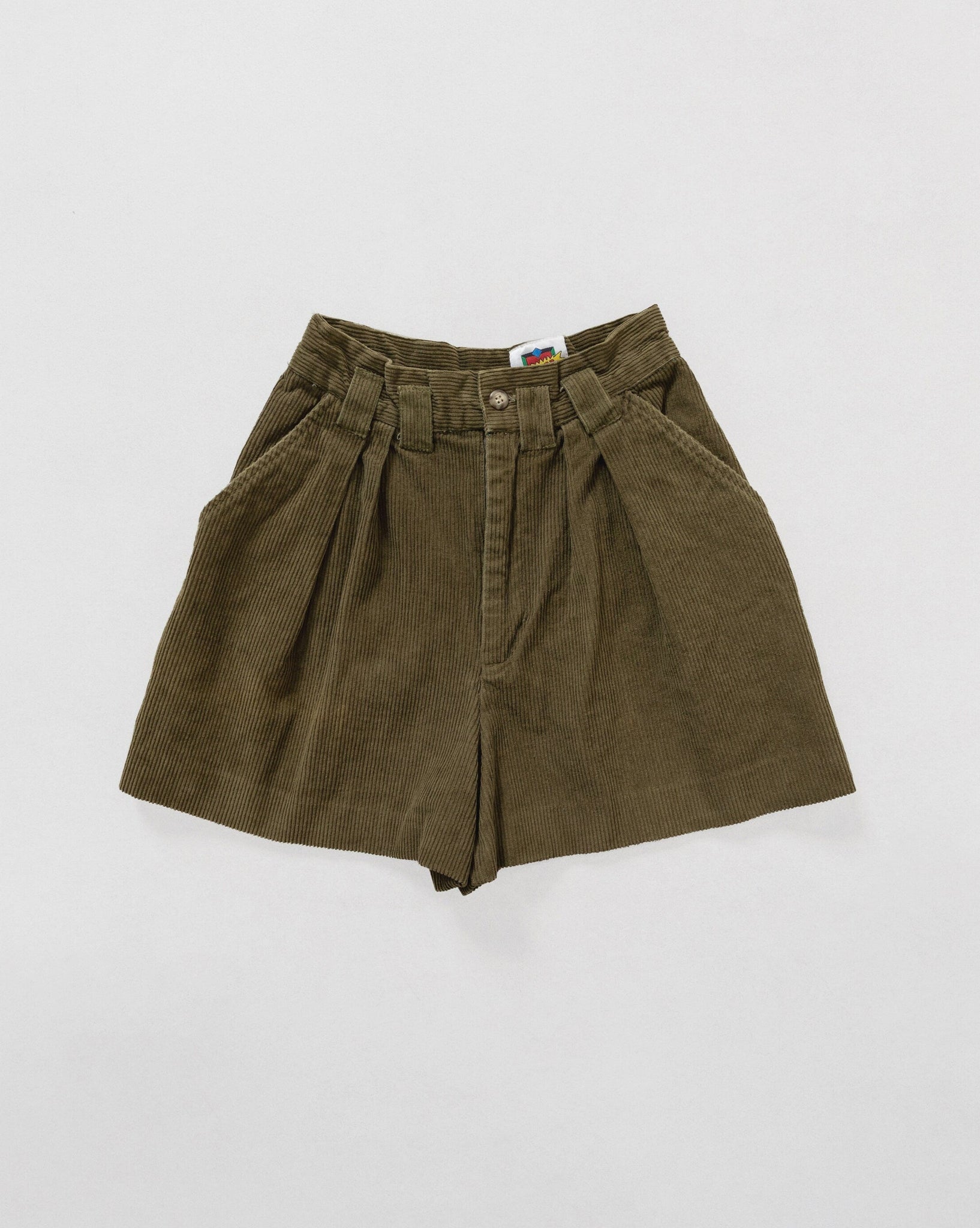 A pair of green high-waisted vintage corduroy shorts with pleats at the waist and a button fly.
